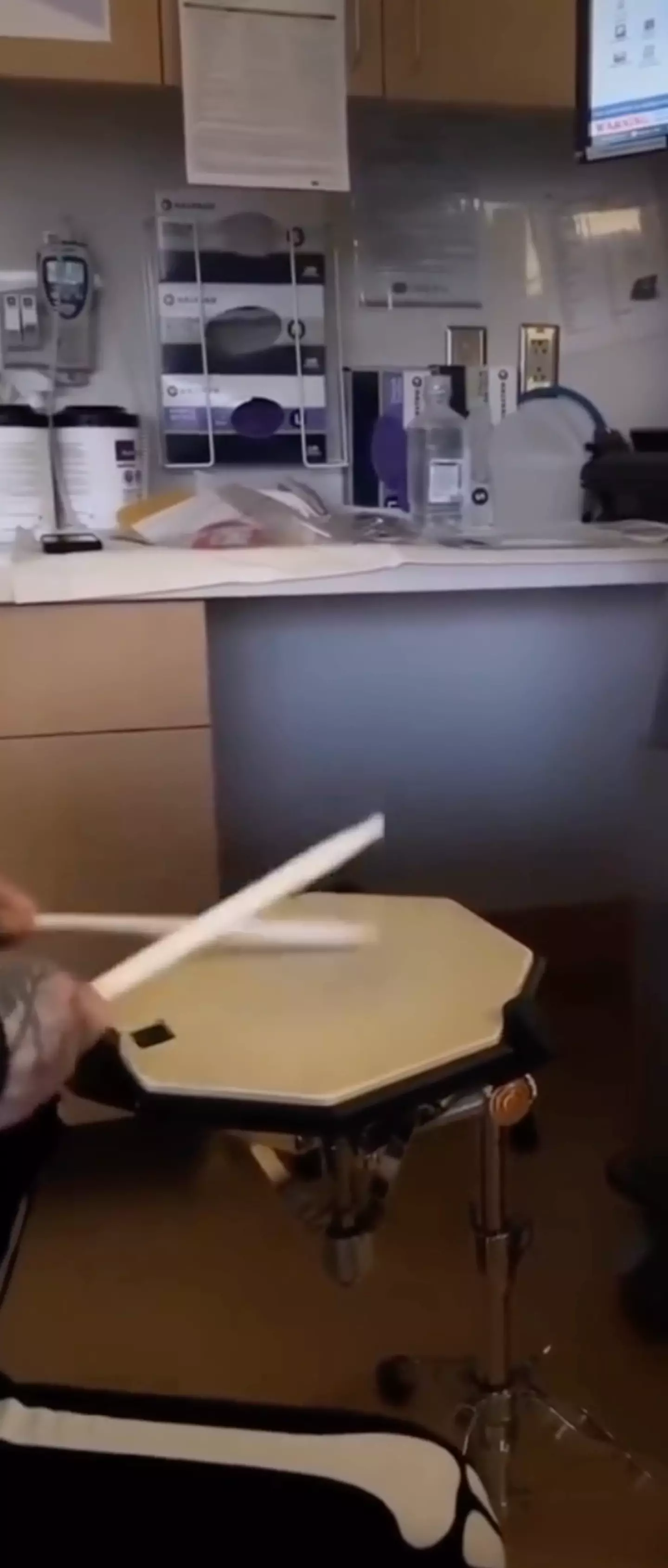 The video shows Travis drumming on a snare drum pad in a doctor's office.