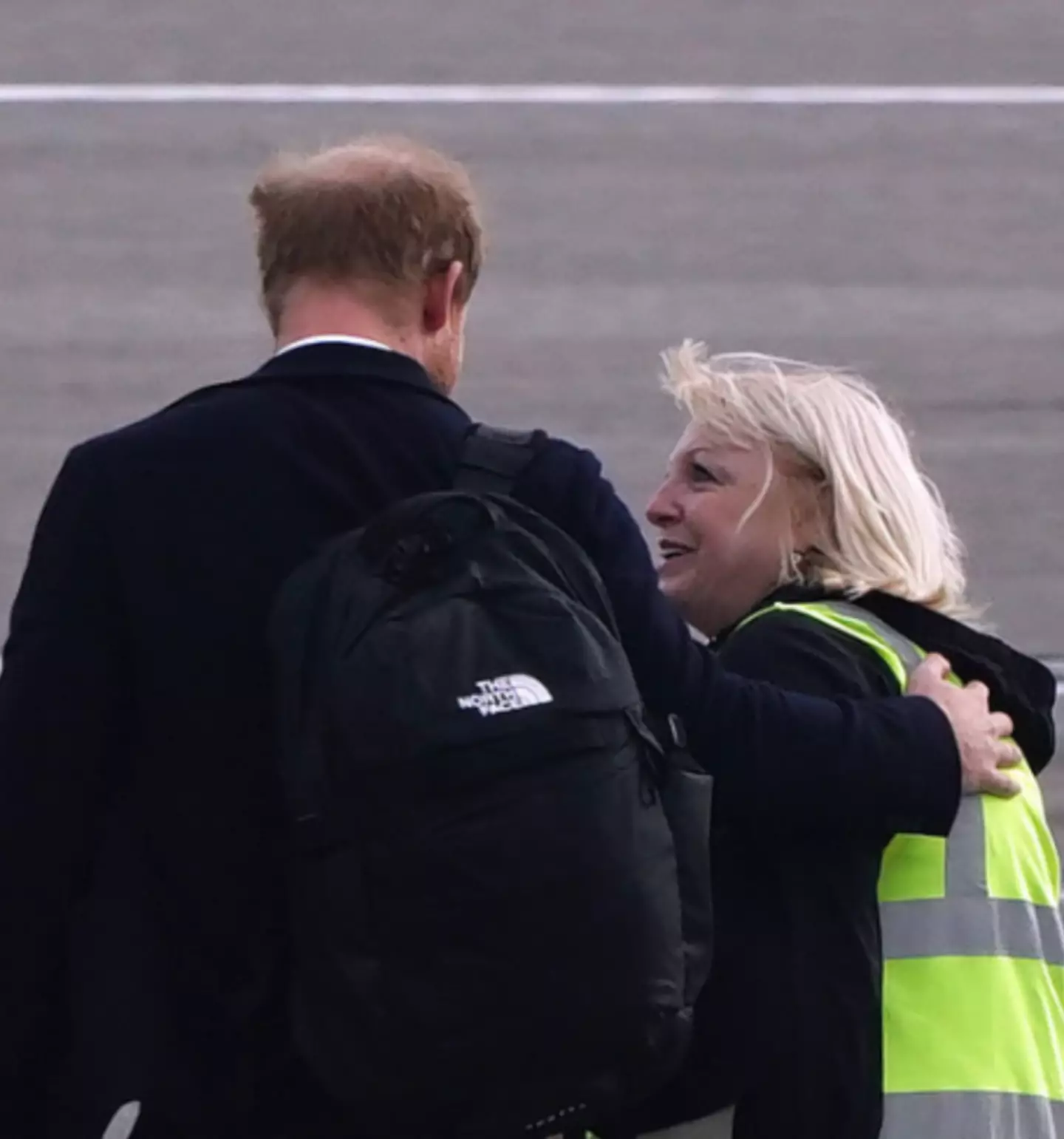 A airport staff member appears to console Prince Harry as he leaves for London on Friday morning.