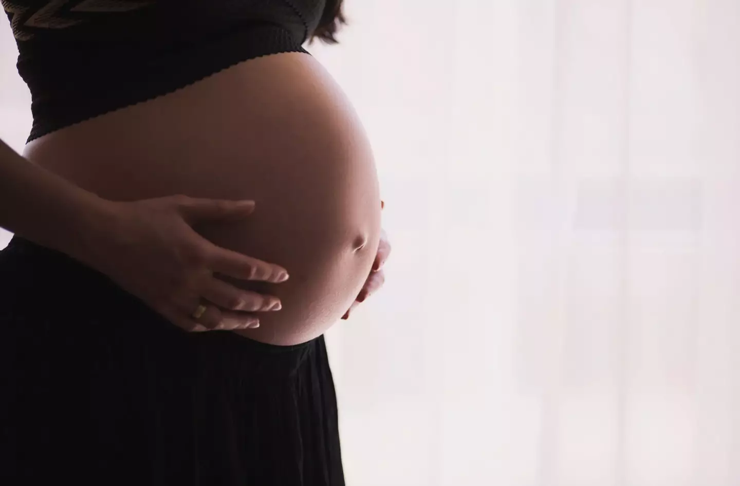 A woman holding her pregnant belly.