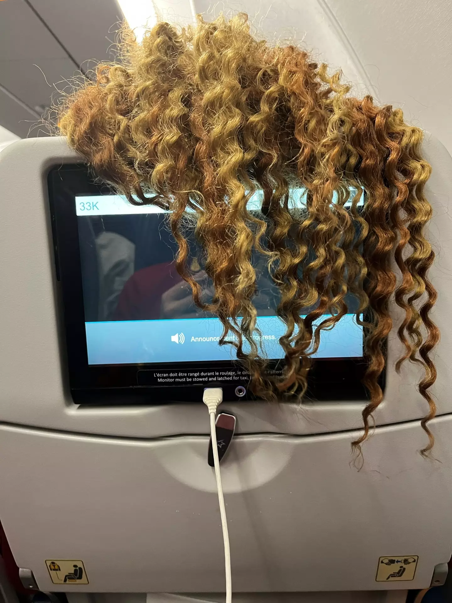 The woman trailed her long tresses down the back of the seat.