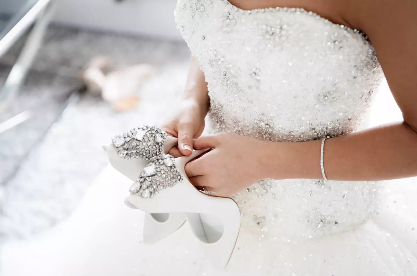 A bride holding shoes.