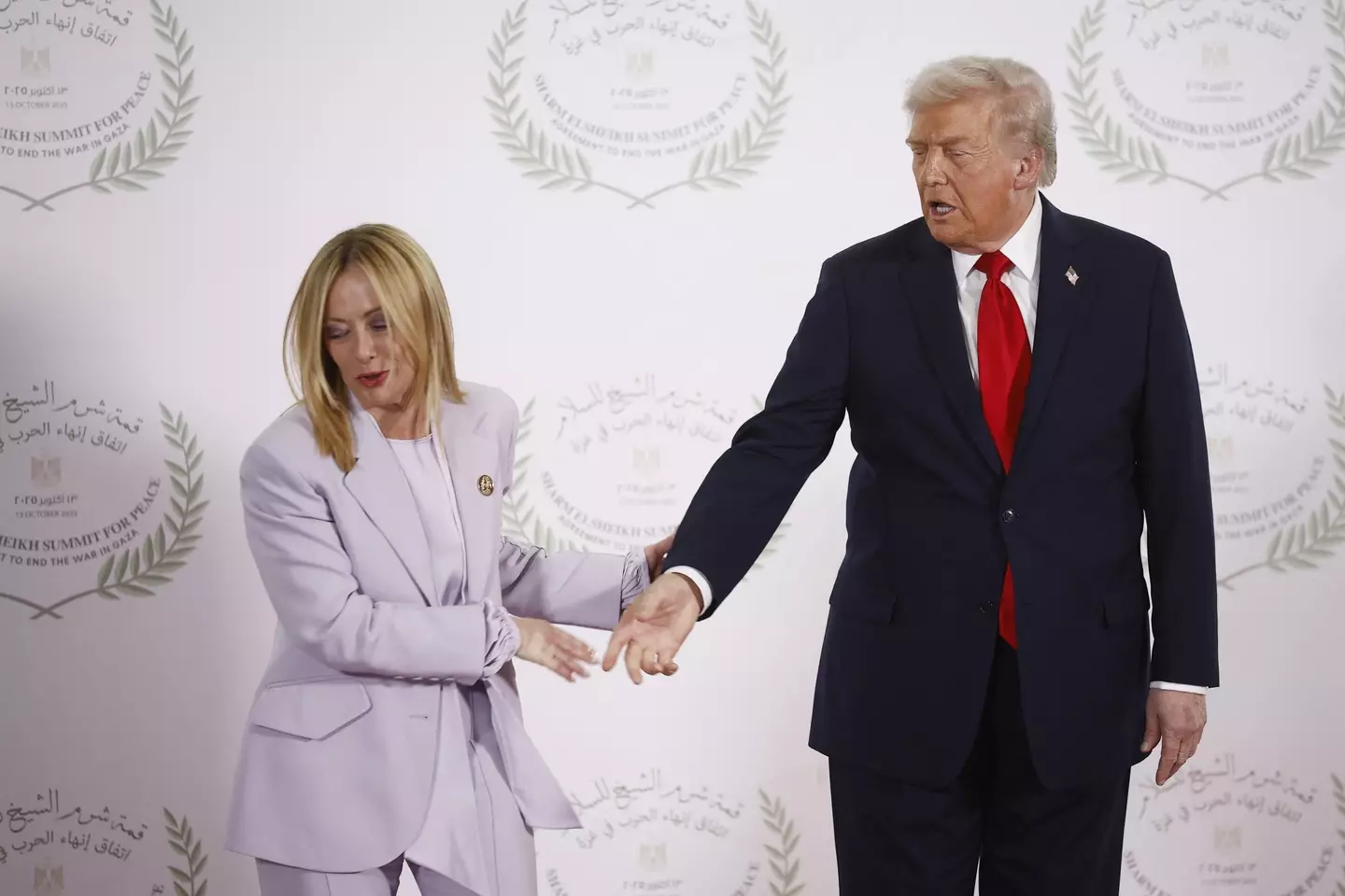 Meloni didn't seem thrilled by Trump's handsy welcome (YOAN VALAT/POOL/AFP via Getty Images)
