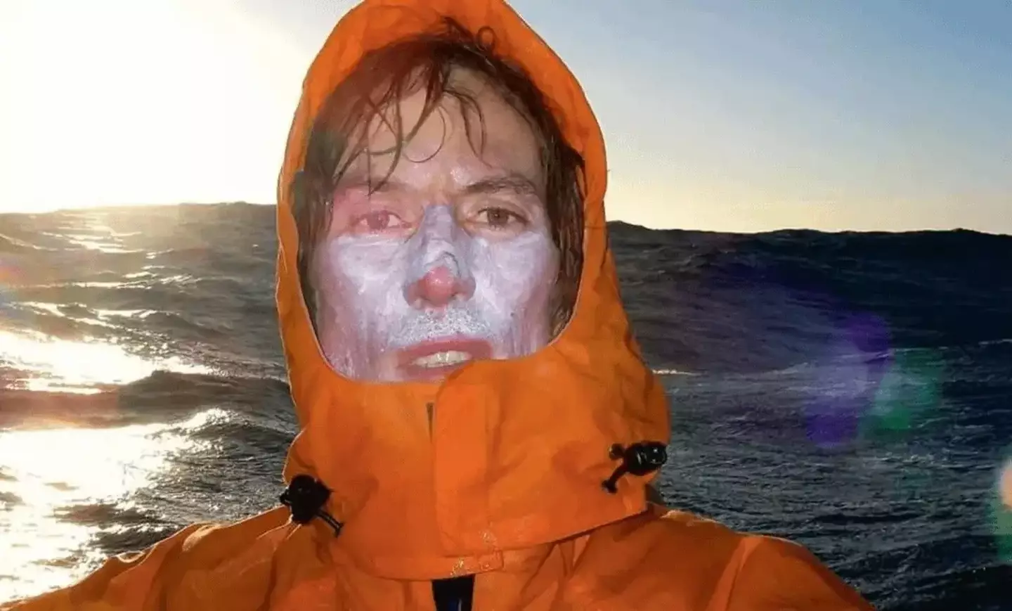 An exhausted McAuley looks directly at the camera as a wave towers behind him (Vicki McAuley)