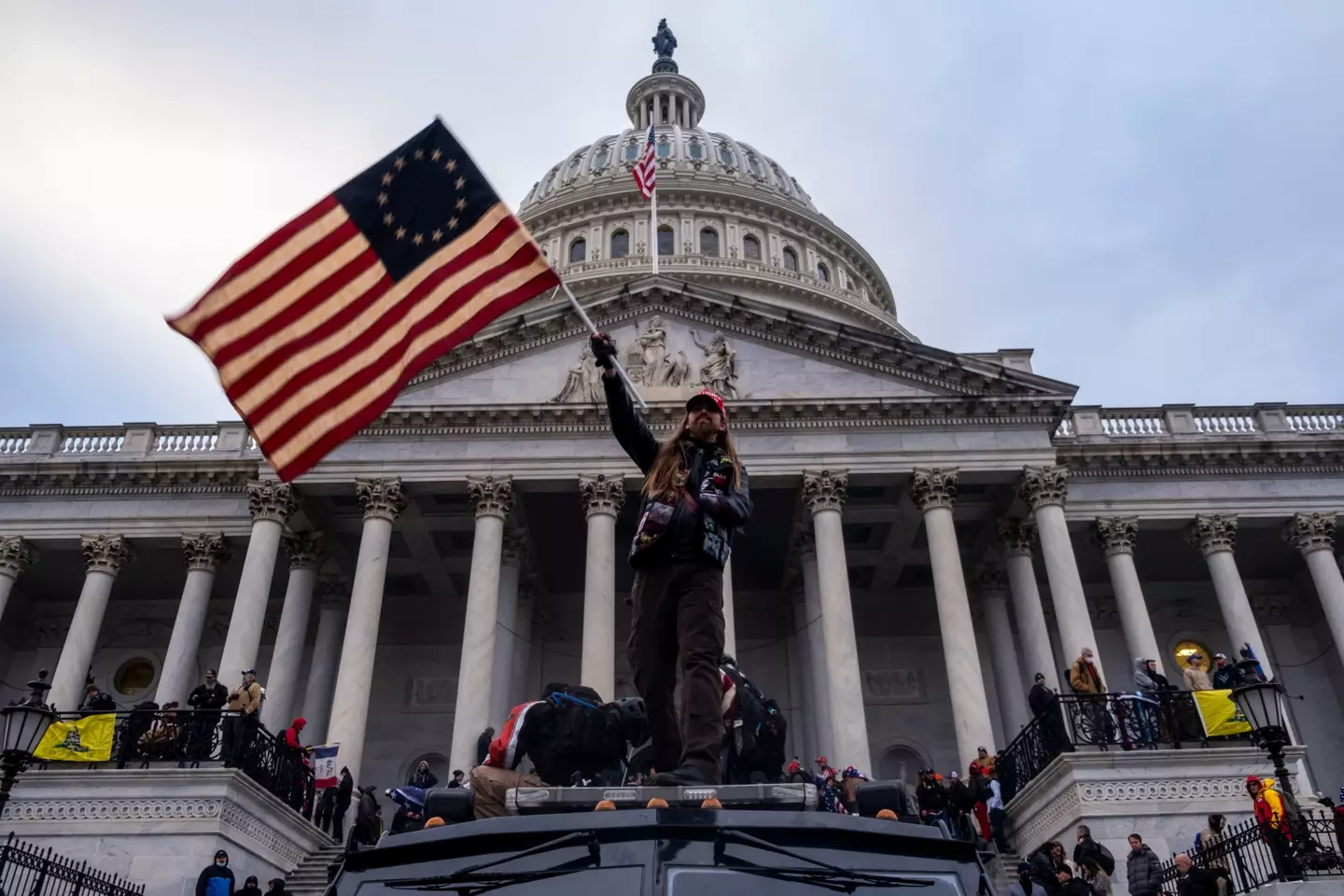 A man waves a flag in front of the Capitol Building during the storming of the building.