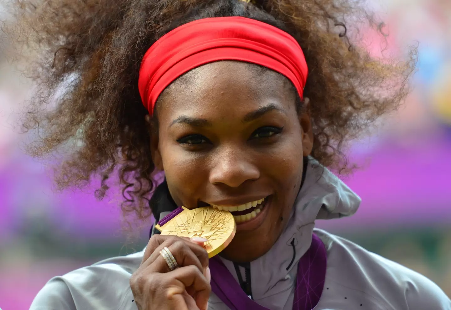Tennis legend Serena Williams biting her gold medal from the 2012 London Olympics. (Luis ACOSTA / AFP) (Photo by LUIS ACOSTA/AFP via Getty Images))