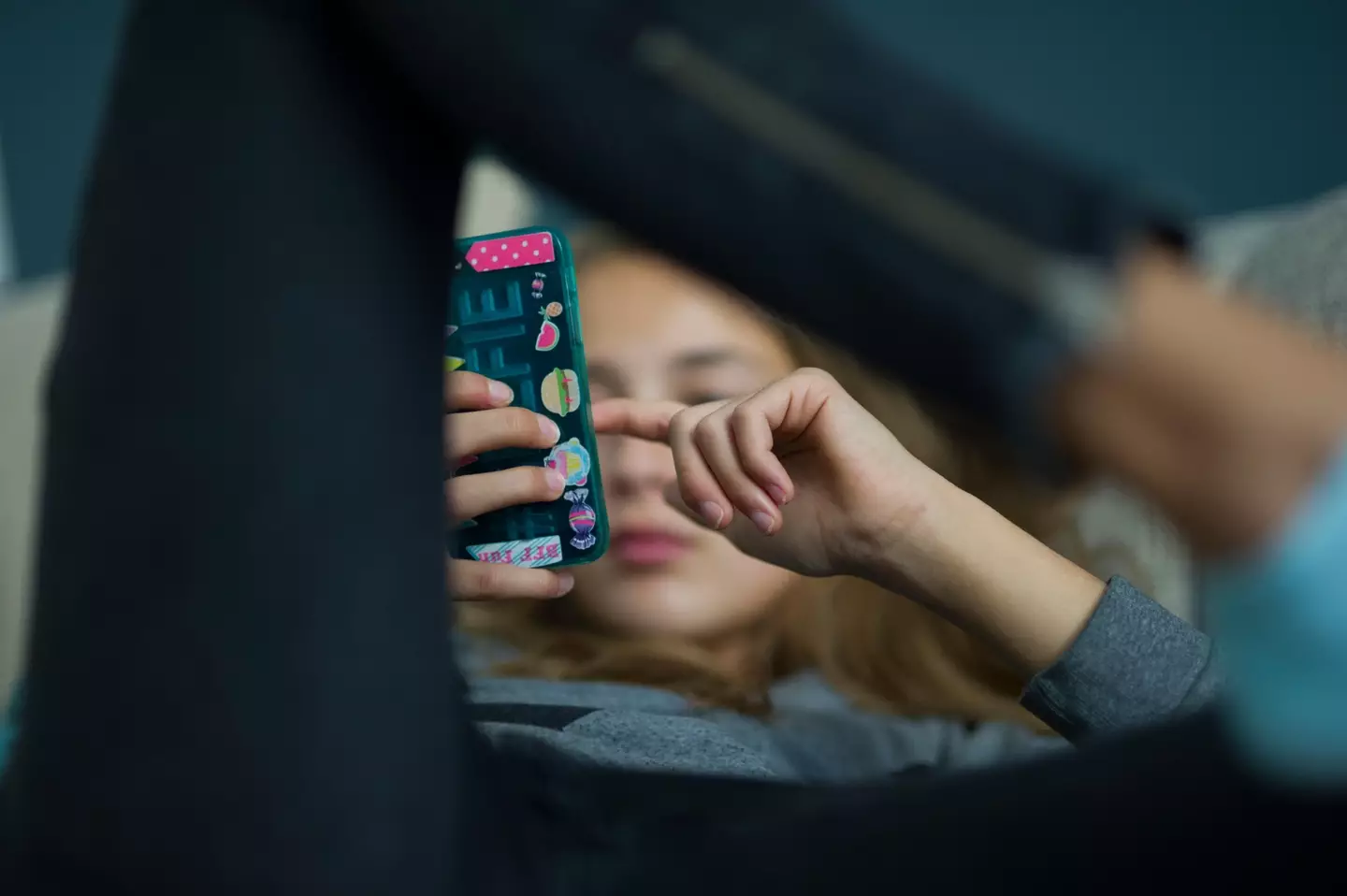 Young girl relaxes with her smartphone on a sofa.