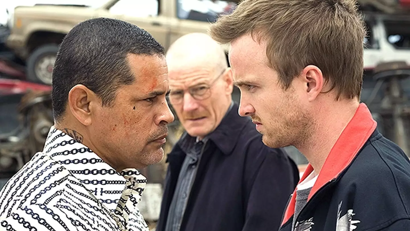 Aaron Paul as Jesse and Raymond Cruz as Tuco, with Bryan Cranston as Walter White in the background.