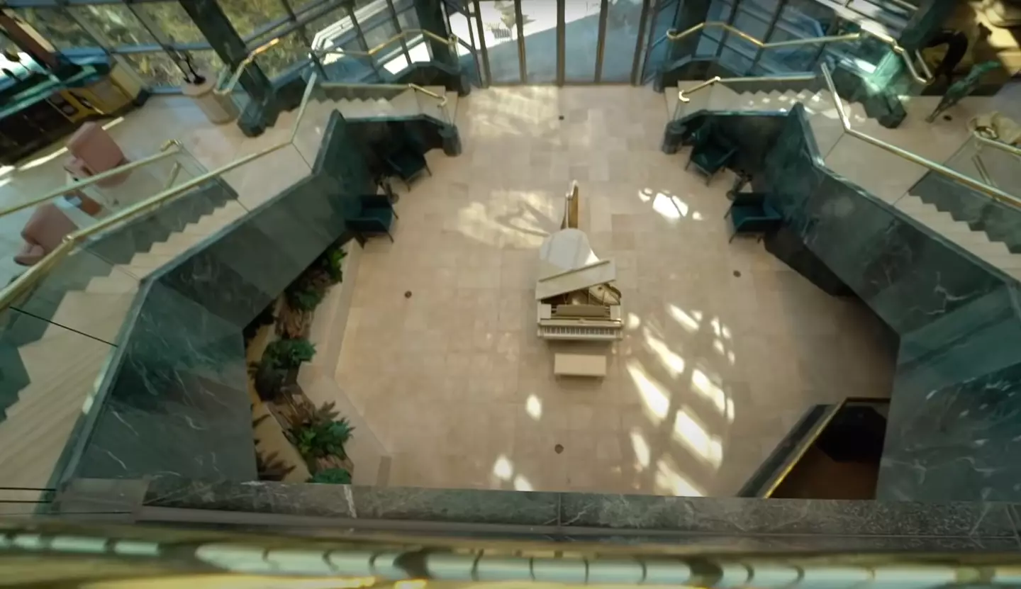 Marble flooring and glistening golden handrails steal the show while a lonesome cream piano sits in the middle of the foyer (YouTube/BigBankz)