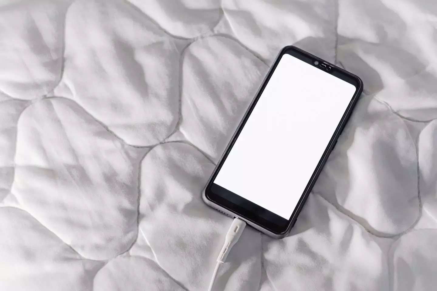 While it might sound dramatic, charging your phone under a duvet or on your bed could cause it to overheat (Getty stock)