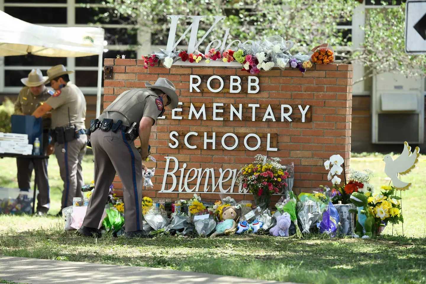 A Texas Department of Public Safety officer places memorials outside Robb Elementary school in south Uvalde where a lone gunman killed 19 schoolchildren and 2 teachers.