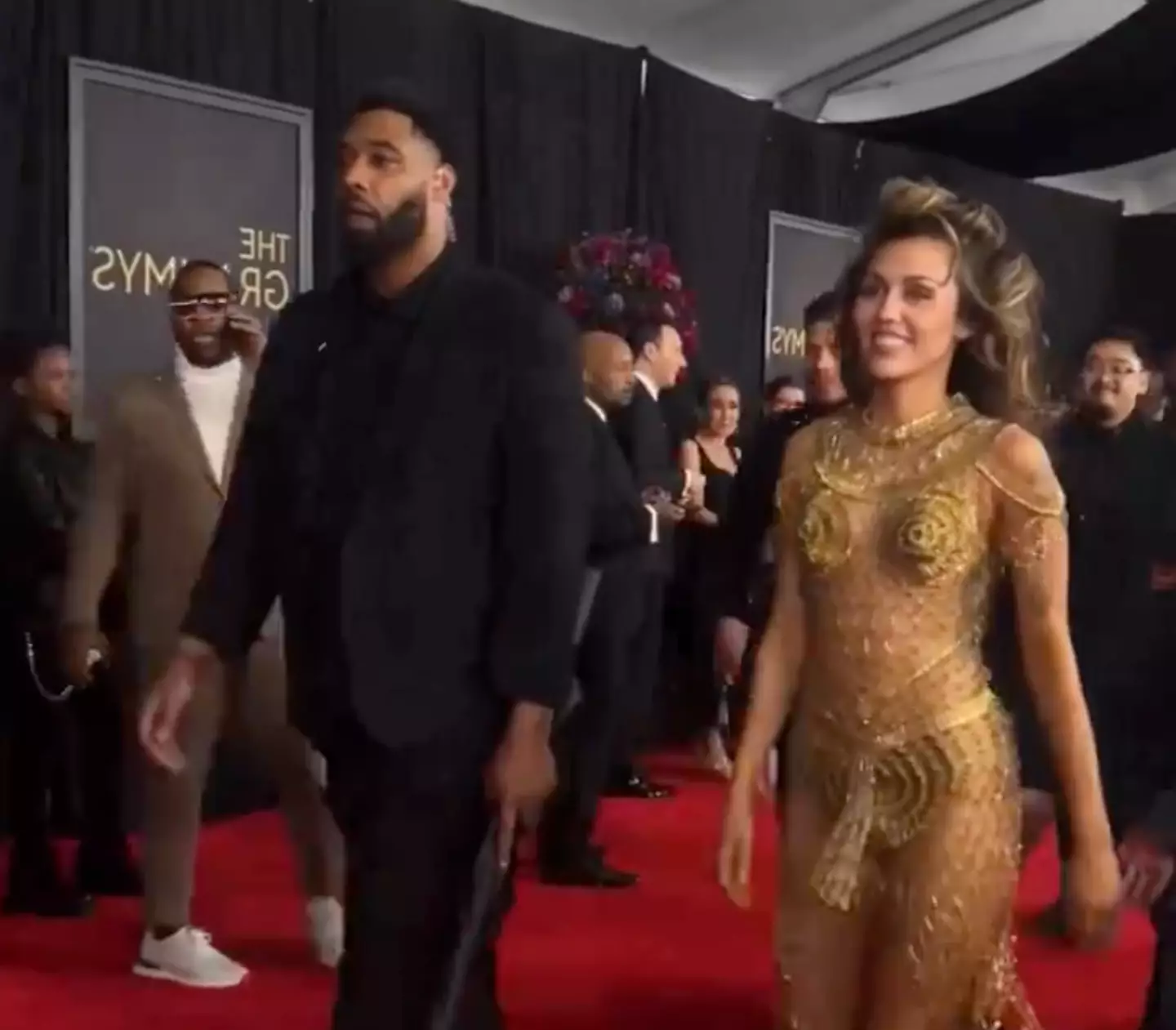 The clip shows Cyrus walking down the red carpet into the ceremony accompanied by her bodyguard who is holding an umbrella.