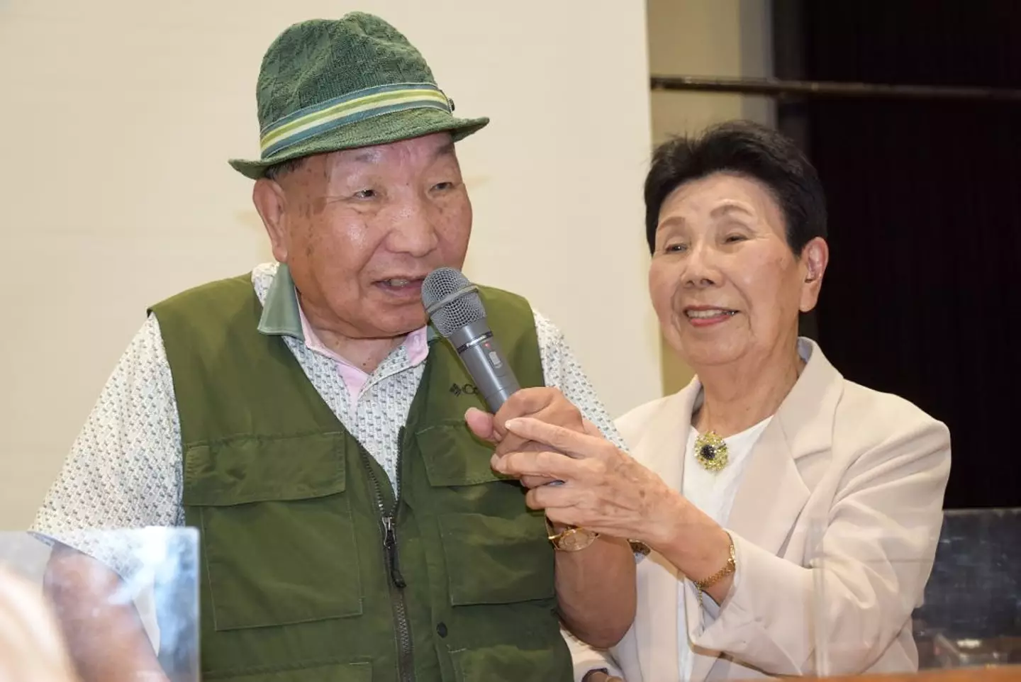 Hakamata speaking as his 91-year-old sister Hideko holds the microphone (STR/JIJI Press/AFP via Getty Images)