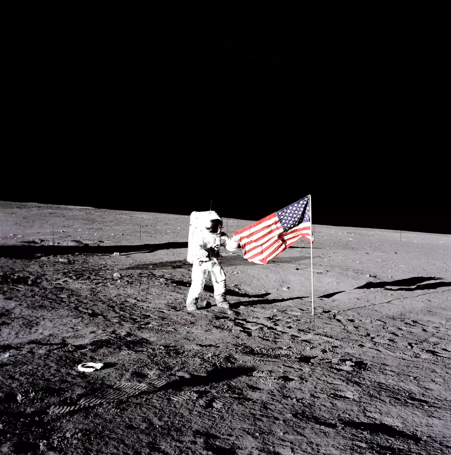 NASA Apollo 12 lunar landing mission astronaut Pete Conrad unfurls the American flag on the lunar surface during his first spacewalk November 19, 1969 on the Moon.