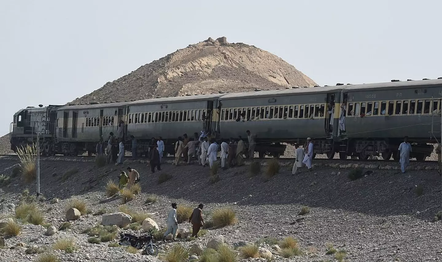 Pakistani passengers gather around a train following two explosions in the town of Much, 55 kilometres east of Balochistan's provincial capital Quetta, back in 2016 (BANARAS KHAN/AFP via Getty Images)