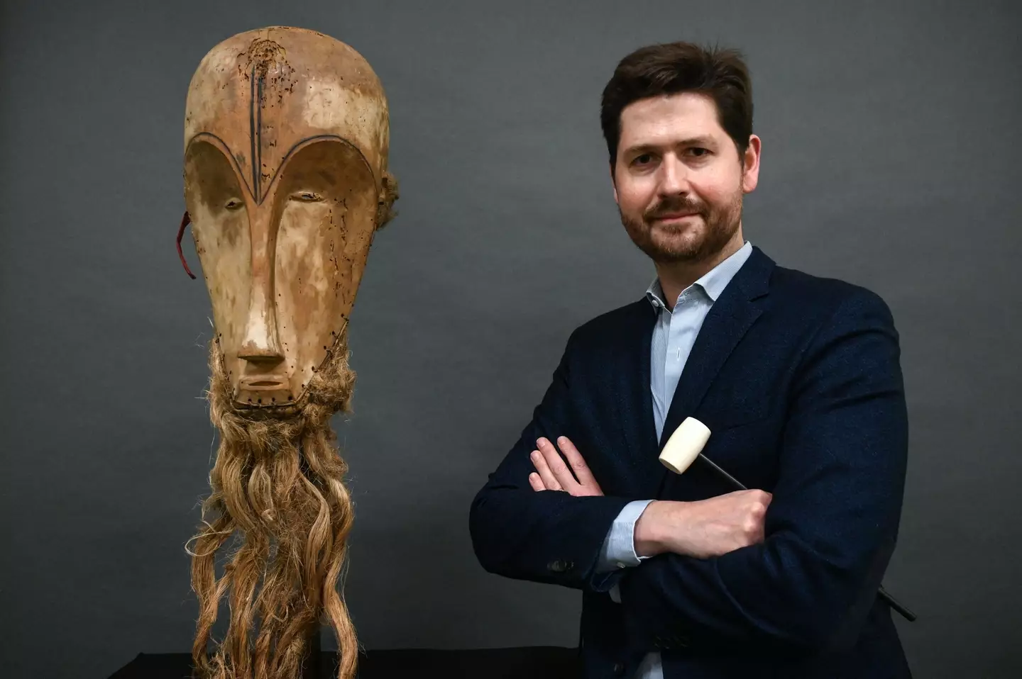 Auctioneer Jean-Christophe Giuseppi poses next to a "Ngil" mask.