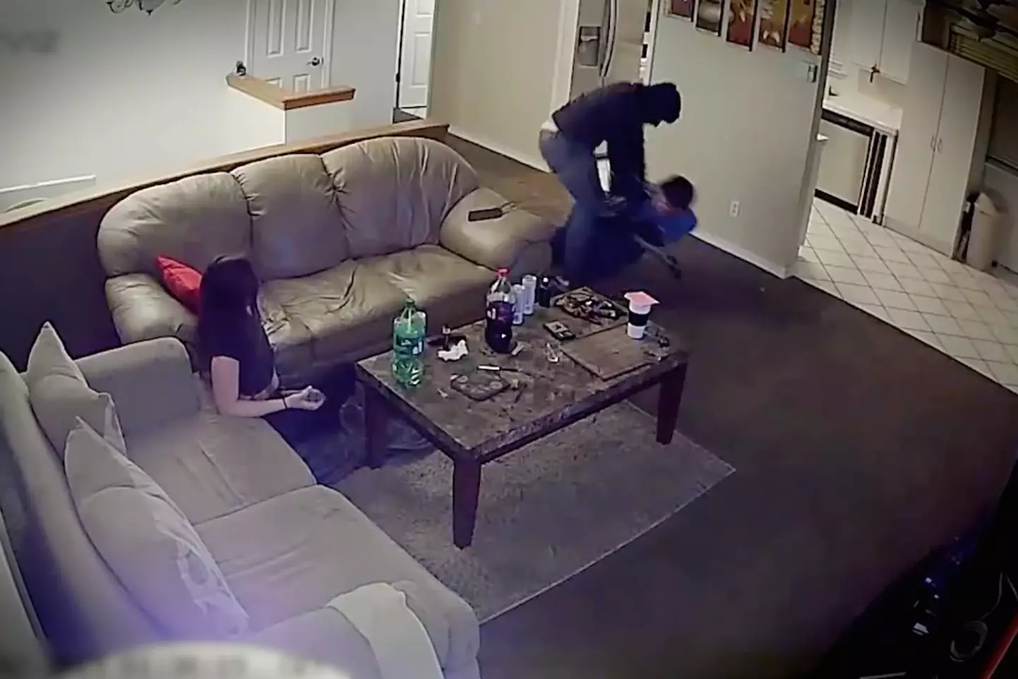 Caspian grabs the barrel of the intruder's shotgun and holds on as he is dragged out of the building.