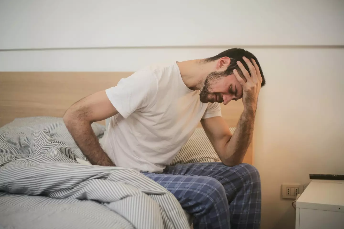 A man deeply upset getting out of bed. (pexels/Andrea Piacquadio)