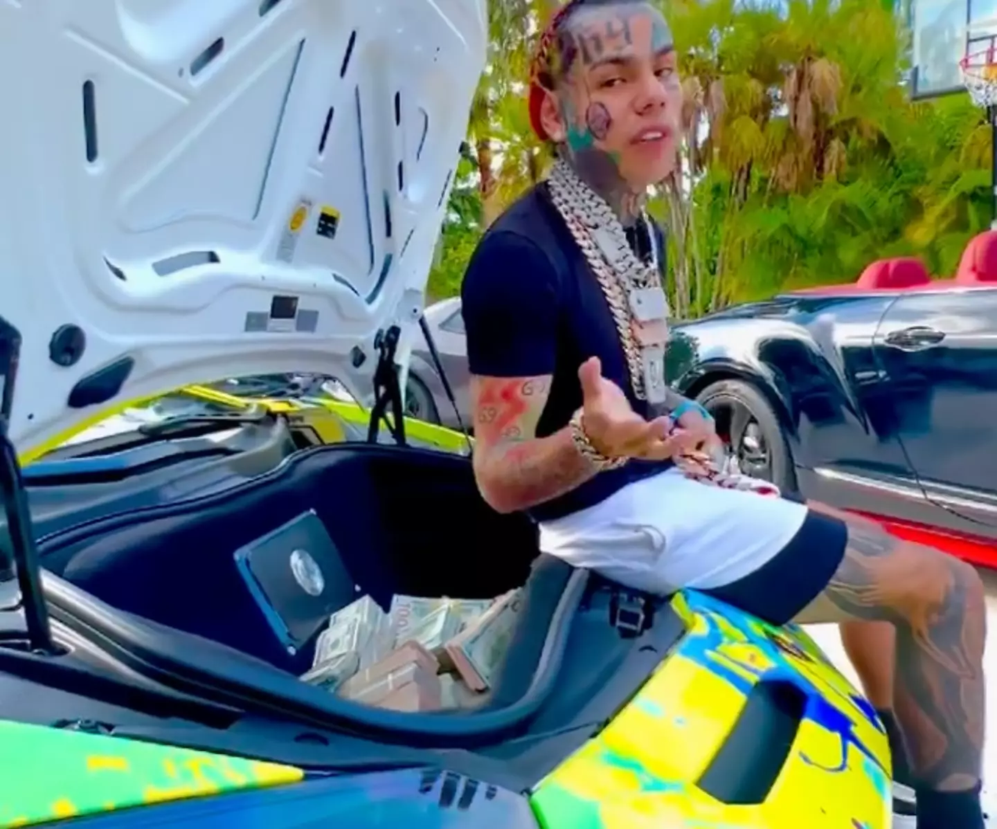 6ix9ine counts out his physical money for his followers while also promoting his new music video.