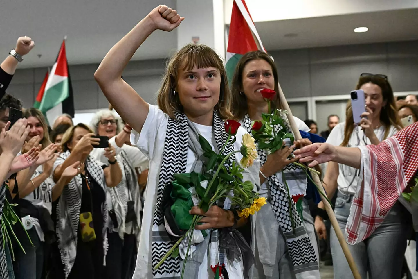 Greta Thunberg raises her fist alongside activists who were sailing aboard vessels from the Gaza-bound aid flotilla before being stopped and detained by Israeli forces (ARIS MESSINIS/AFP via Getty Images)
