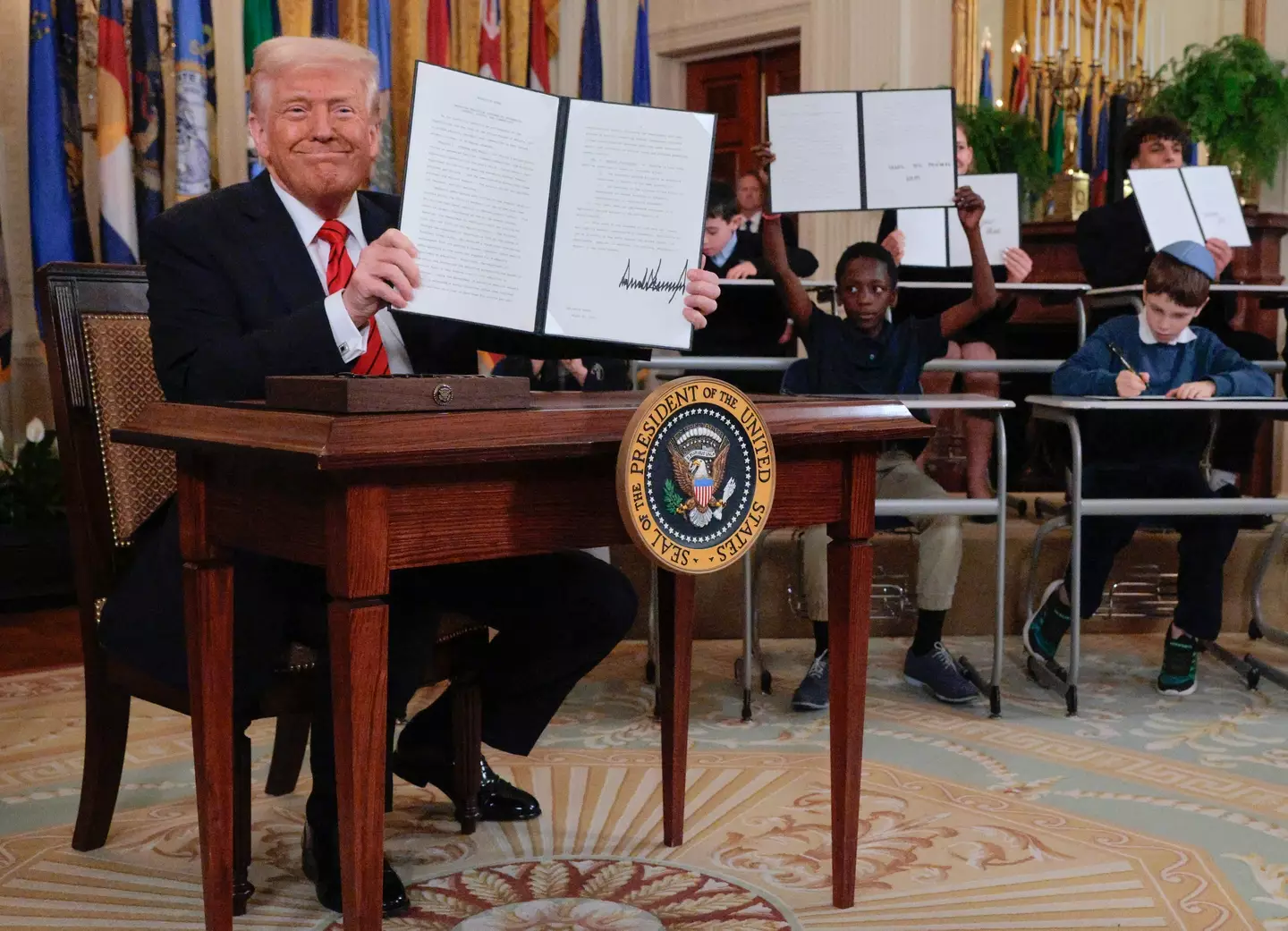 Trump was joined by a group of school kids as he signed the controversial order (Chip Somodevilla/Getty Images)