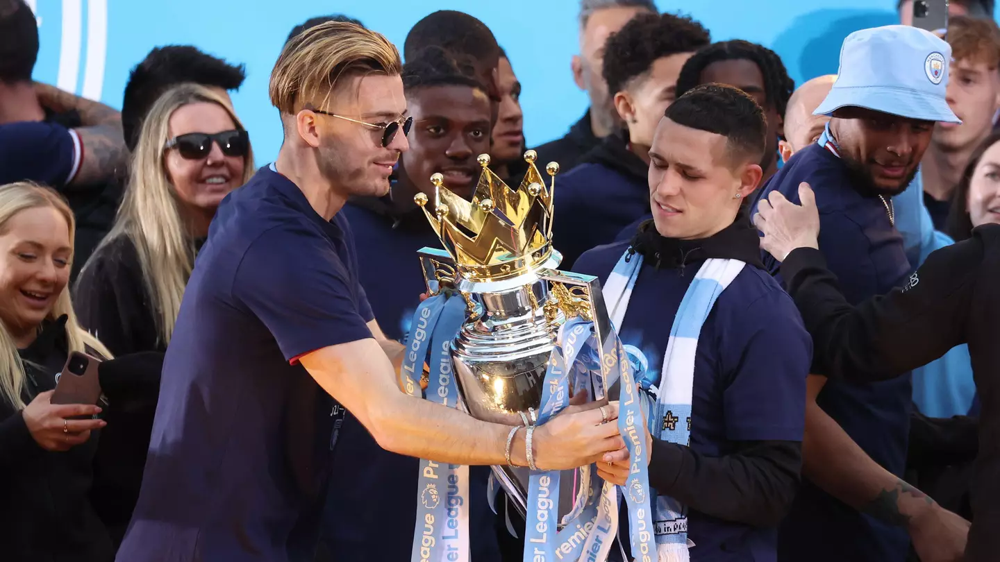 Jack Grealish stands alongside Phil Foden with the Premier League trophy