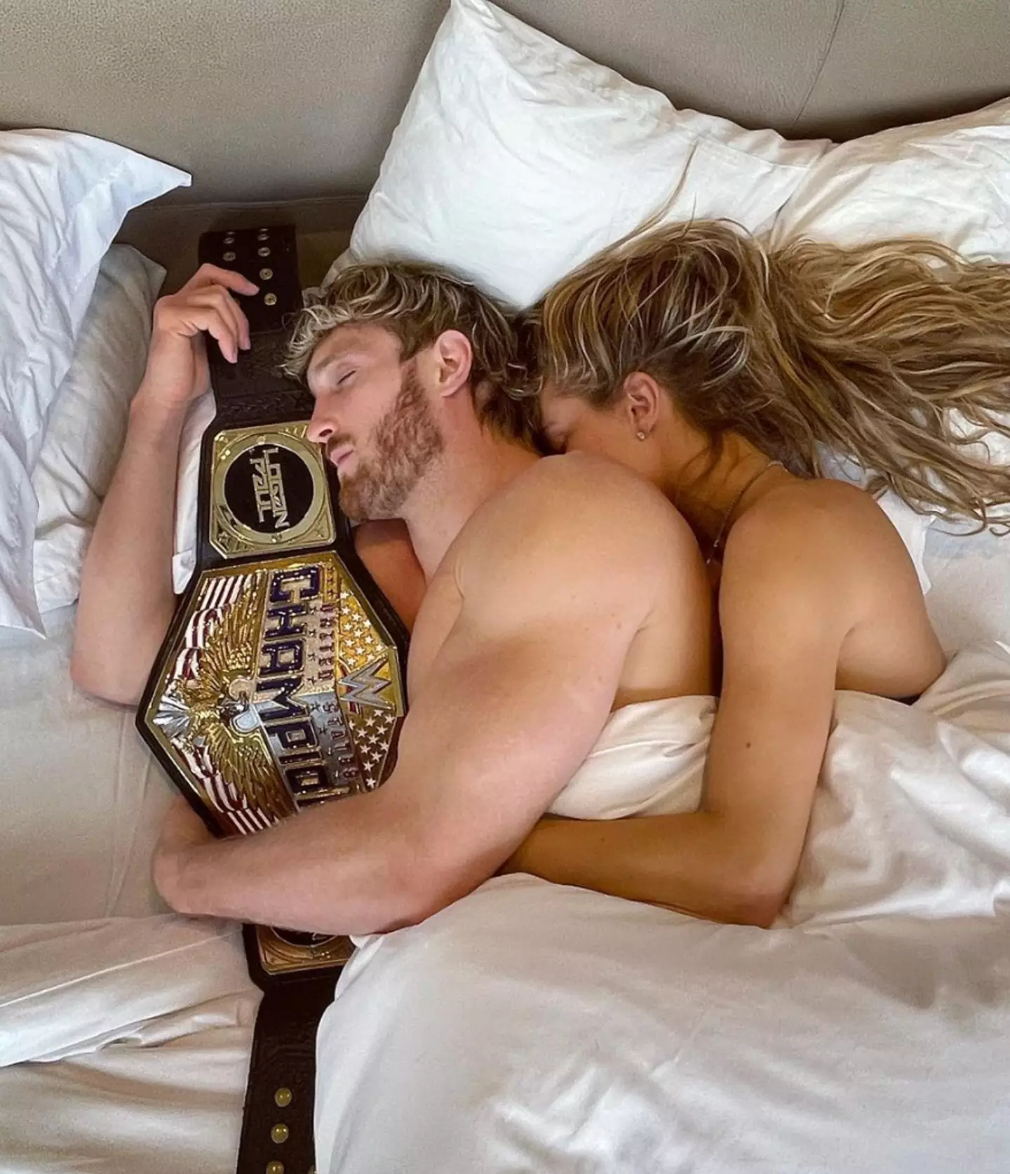 Paul holding the United States Championship in bed alongside fiancee Nina Agdal. (Image