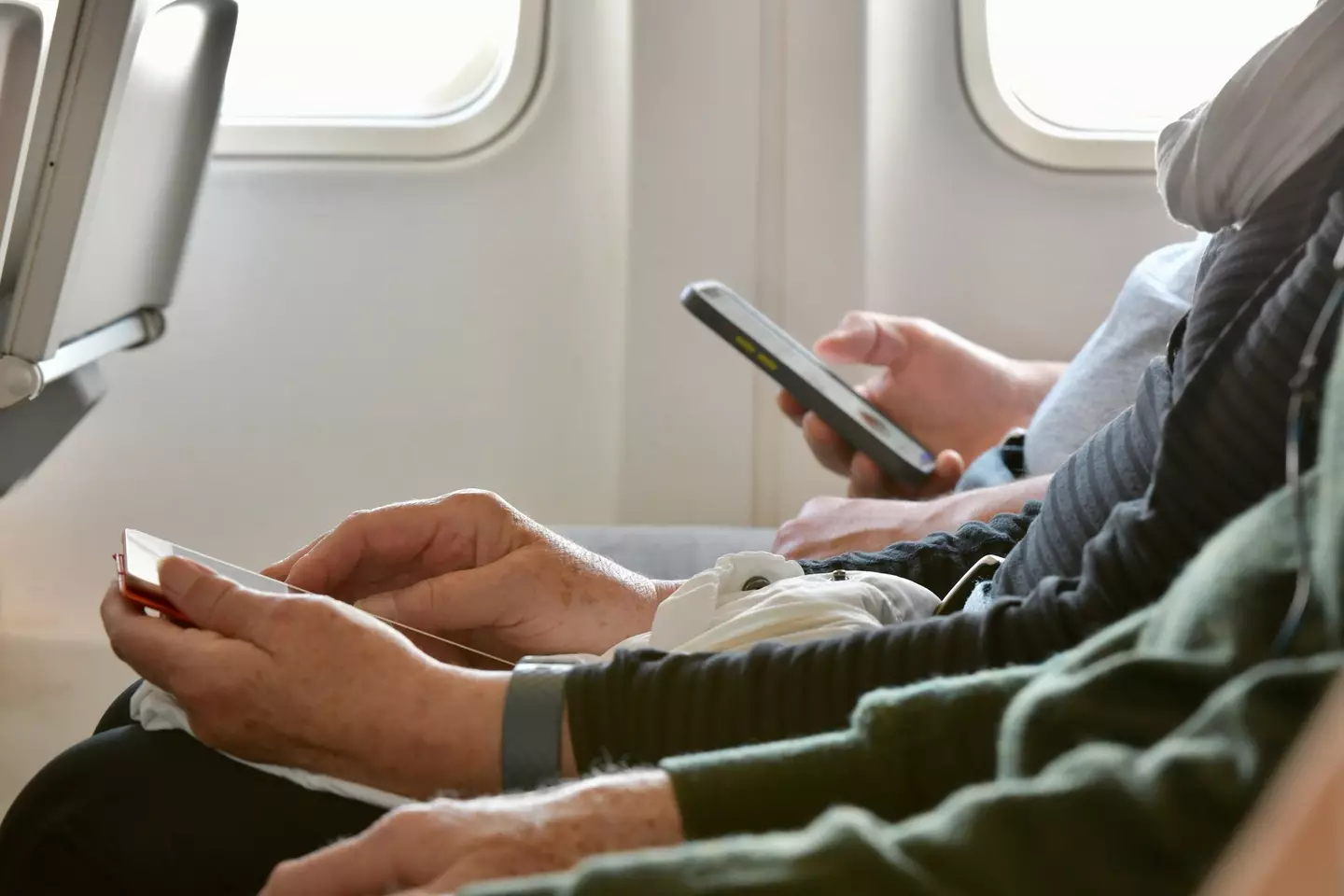 Older person using smartphone on plane (Getty Images)