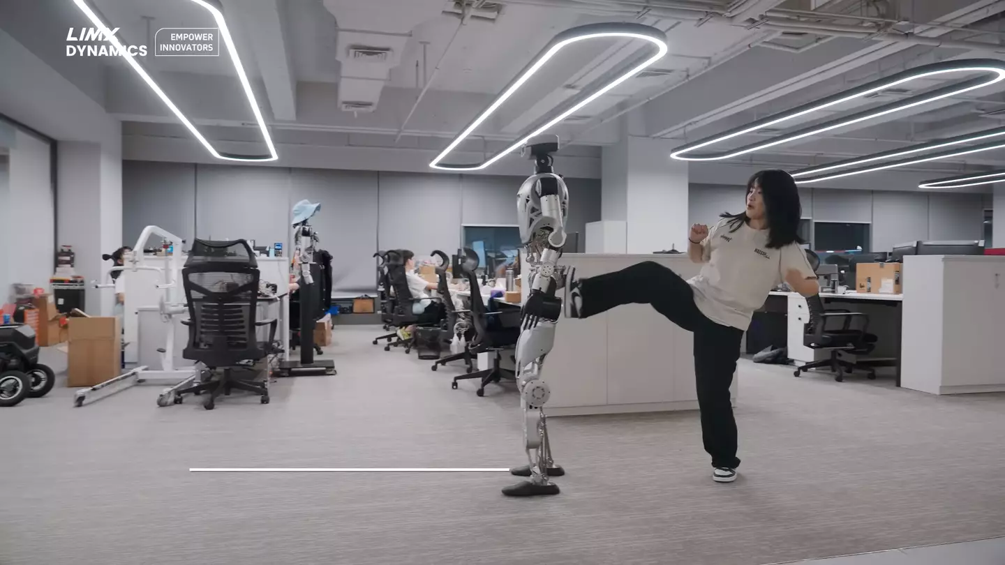 Oli gets a kicking from a human coworker for slacking off (YouTube/LimX Dynamics)