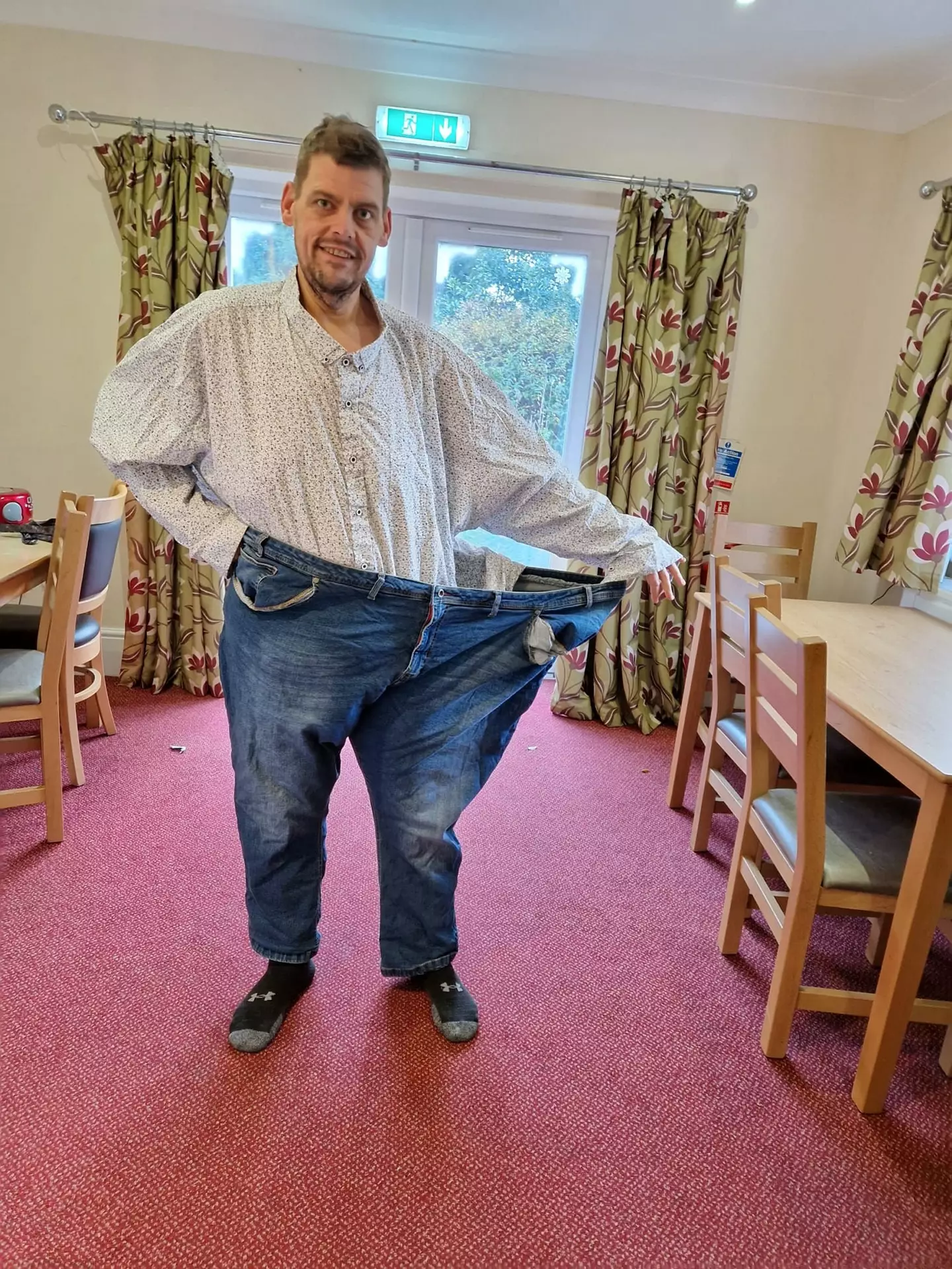 Ashley showing just how much weight he's lost compared to the clothes he would normally buy.