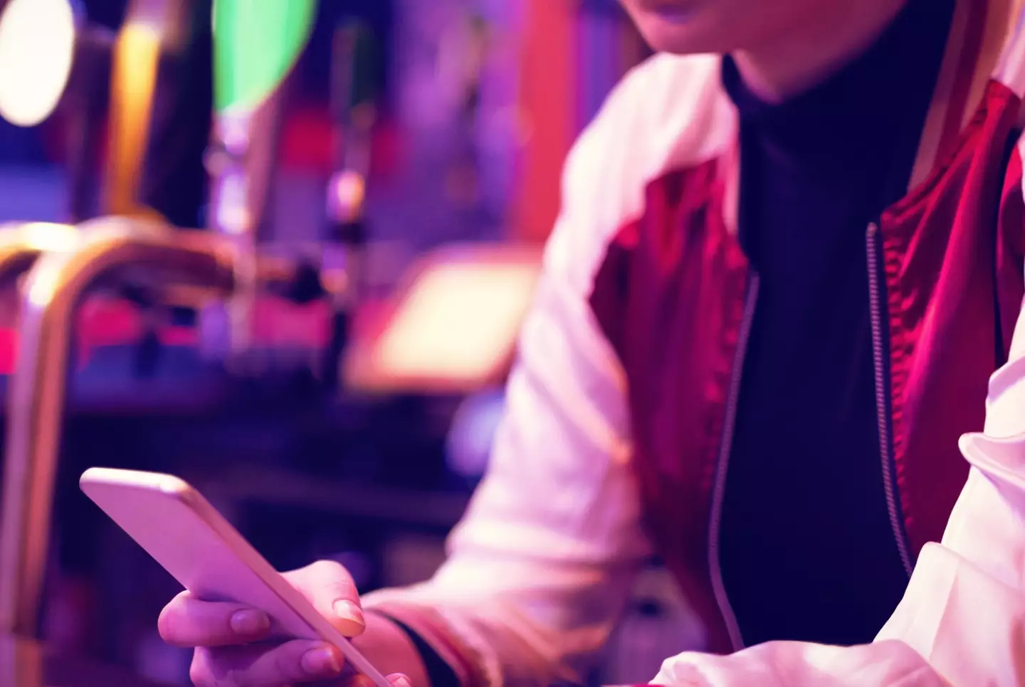 Stock image of bartender using their phone behind the bar.