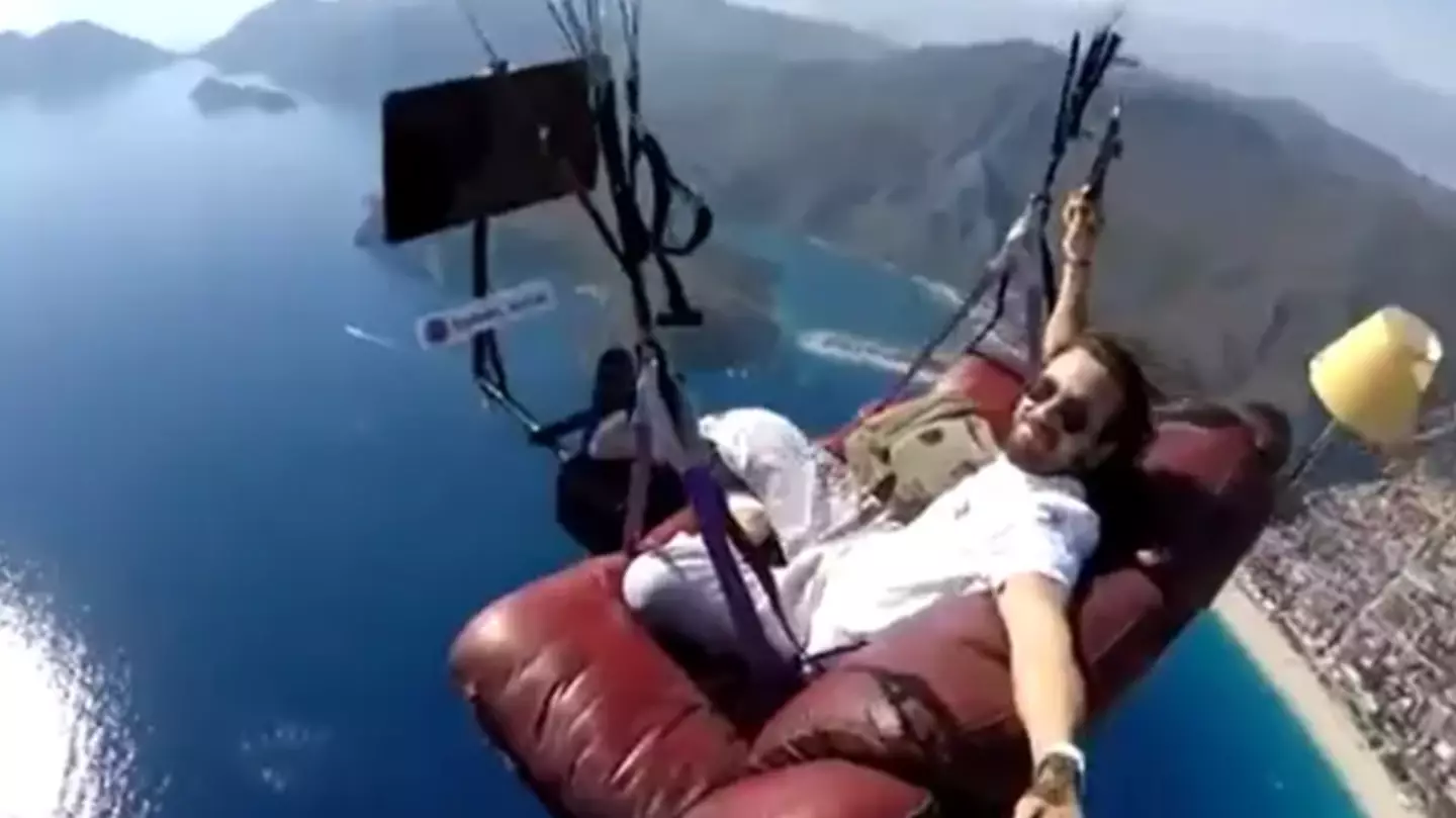 Paragliding instructor soars through the skies while chilling on a couch watching the TV