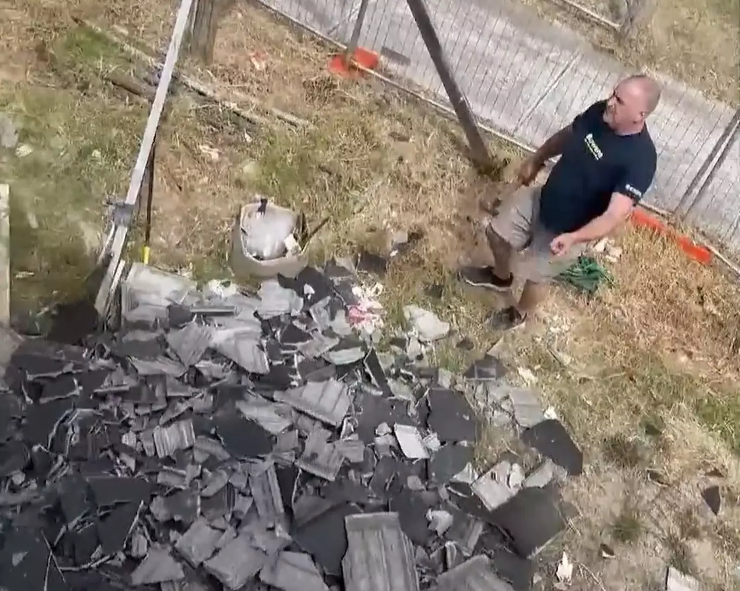 Adrian Padoin standing next to a huge pile of smashed roof tiles.