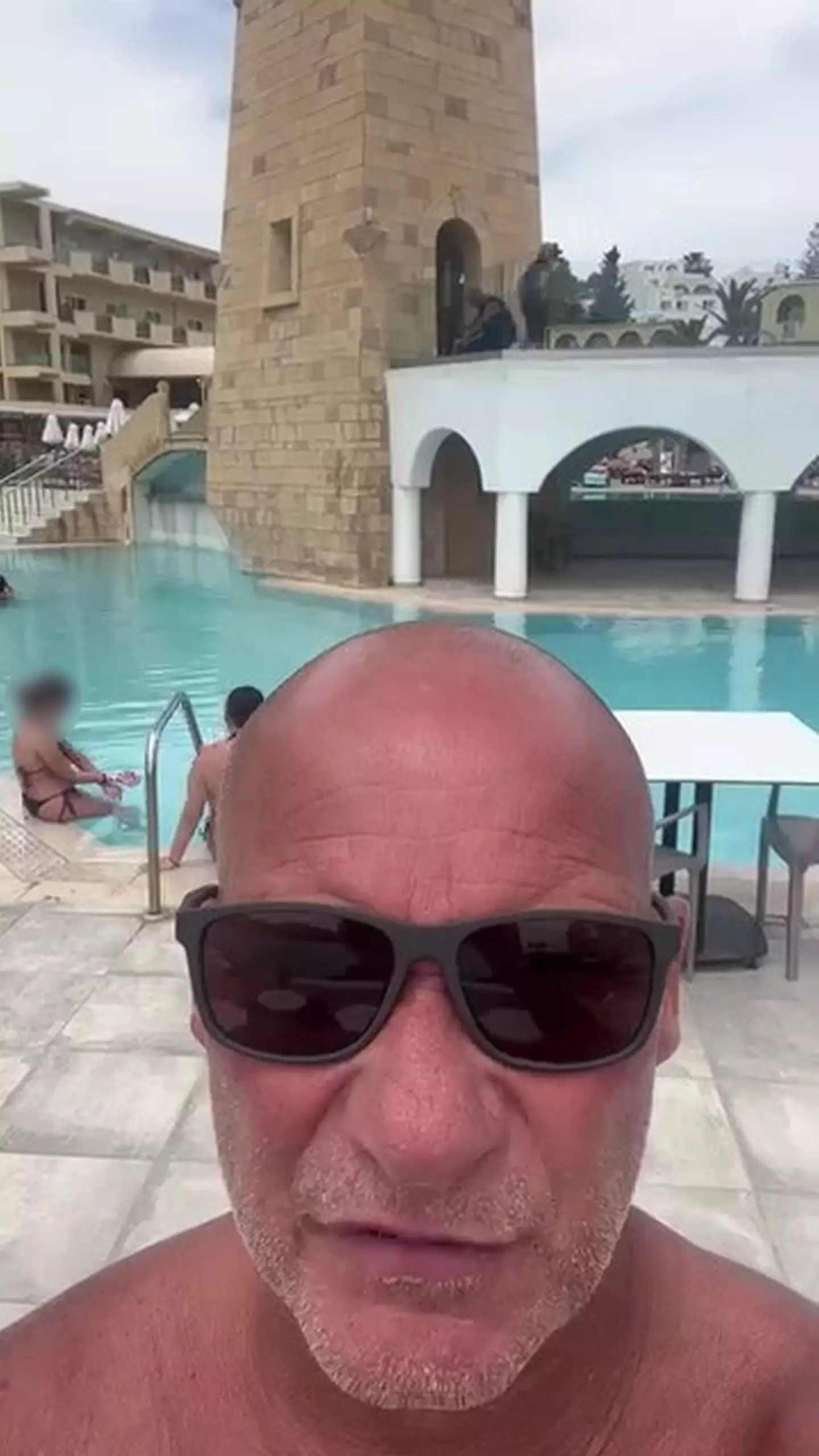 Construction workers can be seen working above the pool while holidaymakers took a dip (Kennedy News and Media)