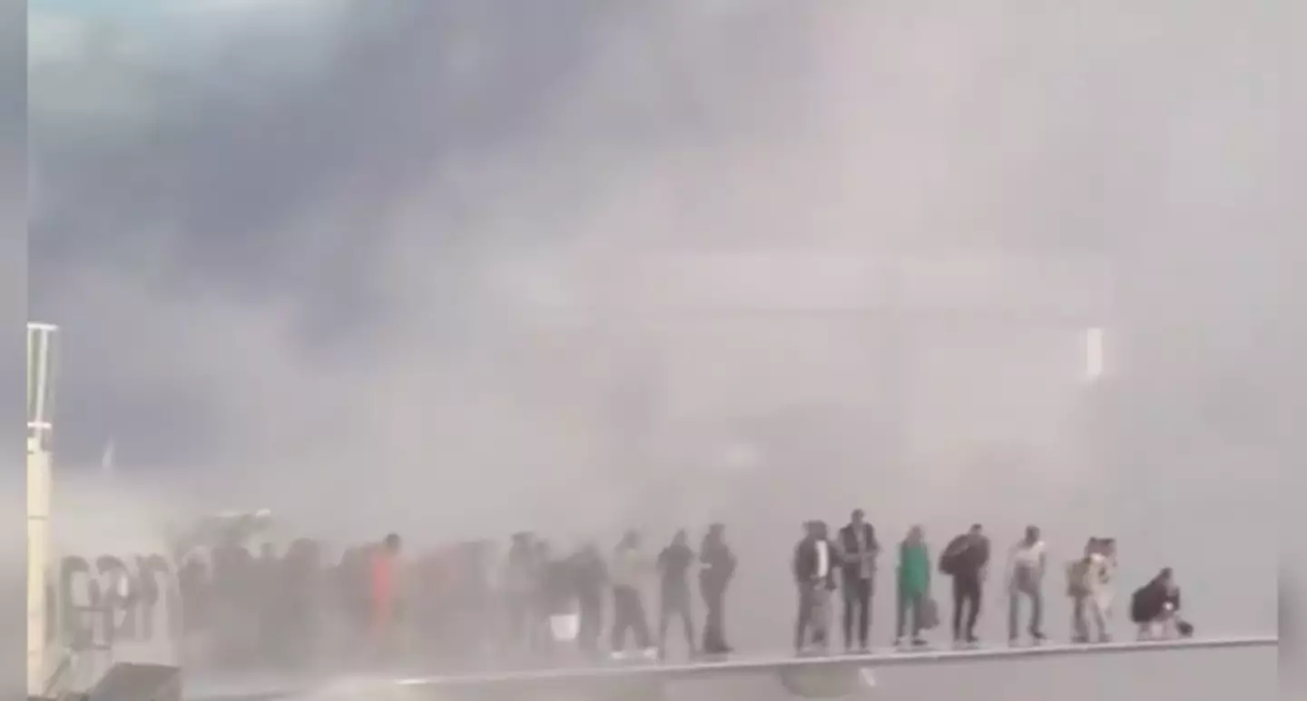 The passengers could be seen huddling on the wing as smoke billowed (X/flynnstone)