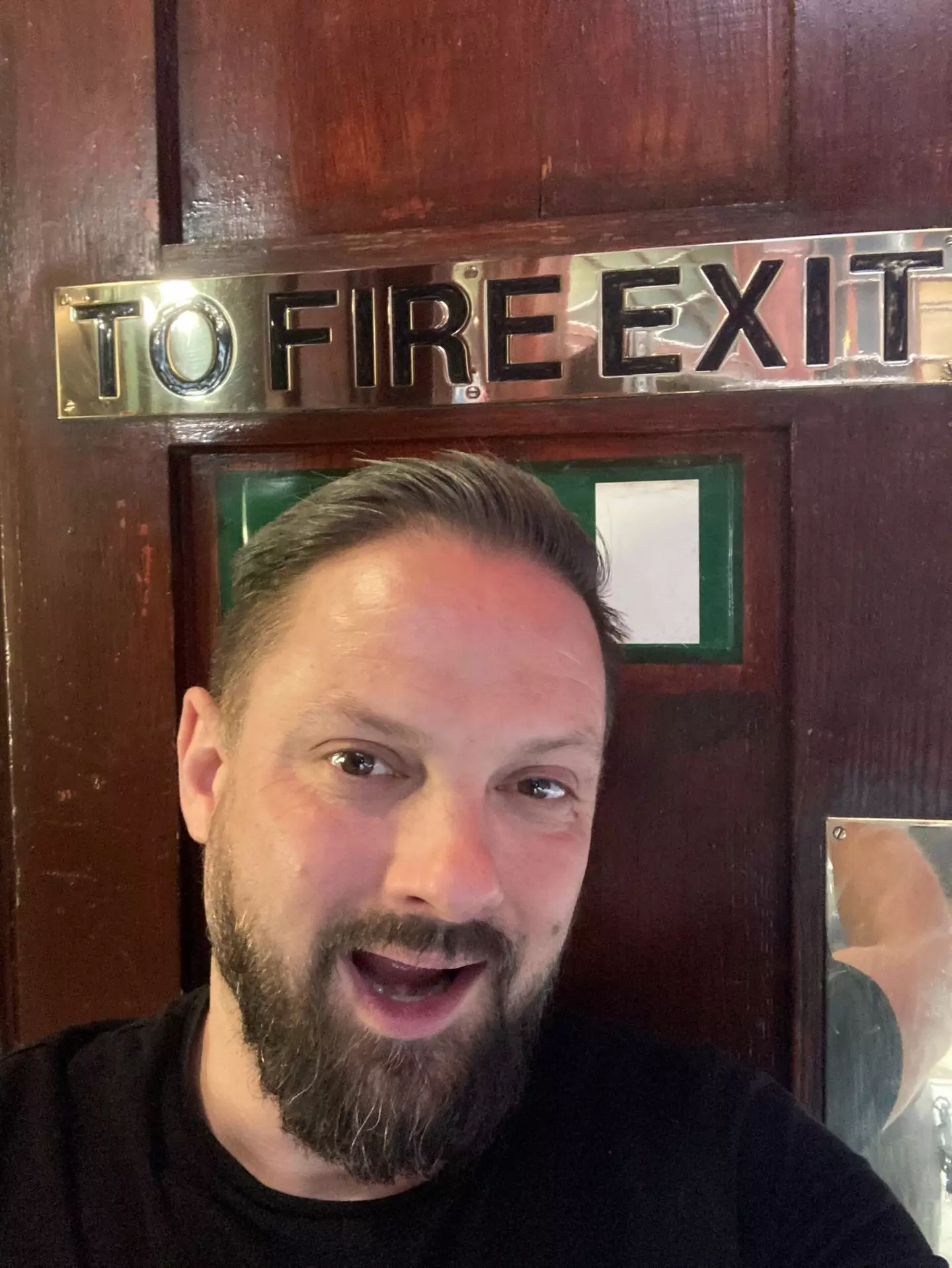 Presumably he's going to be posing next to fire exit signs for the rest of his days.