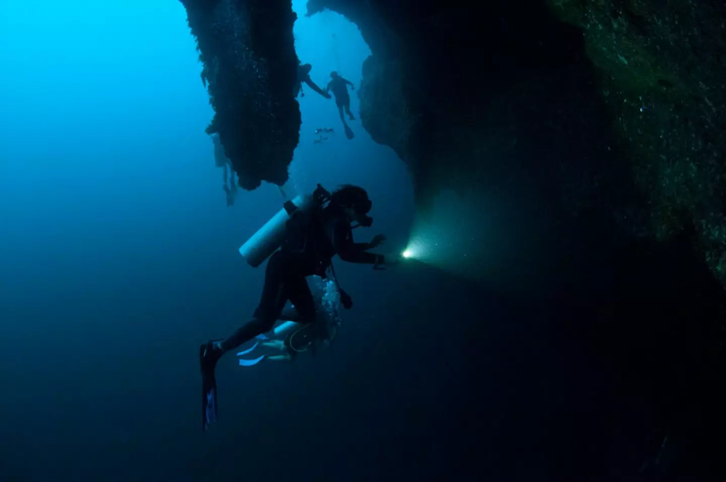 Scuba divers exploring the stalactites.