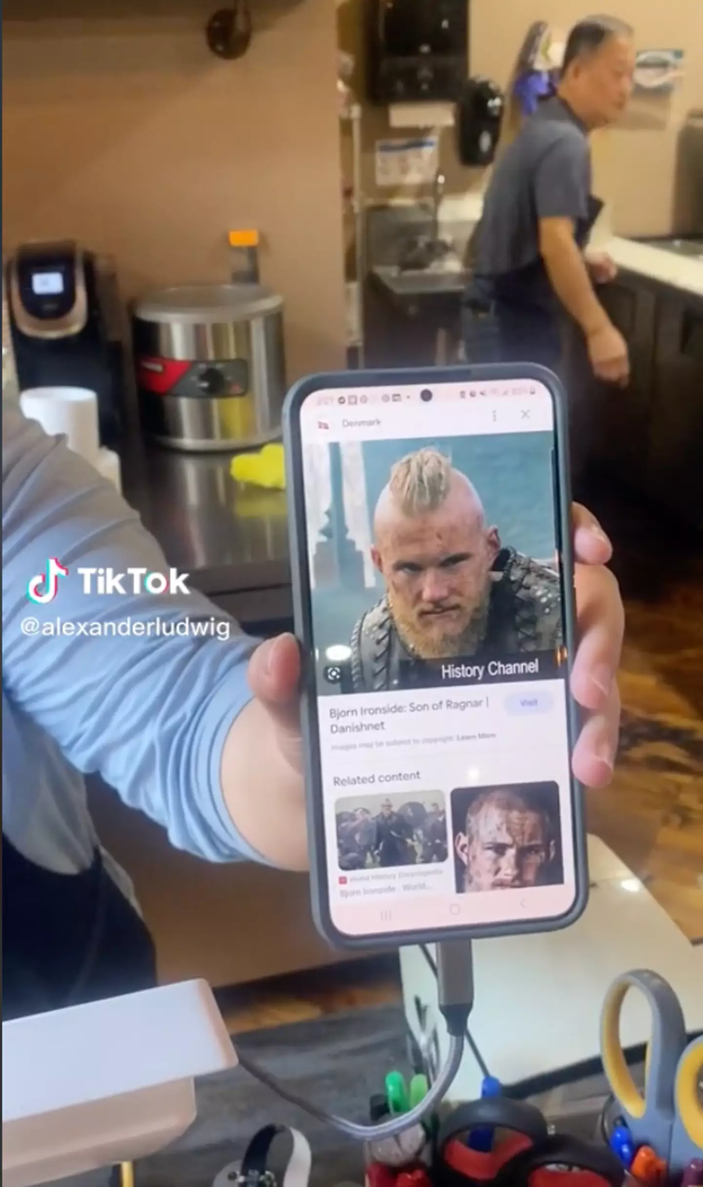 The coffee shop worker held up her phone to show Alexander Ludwig a photo of… Alexander Ludwig.