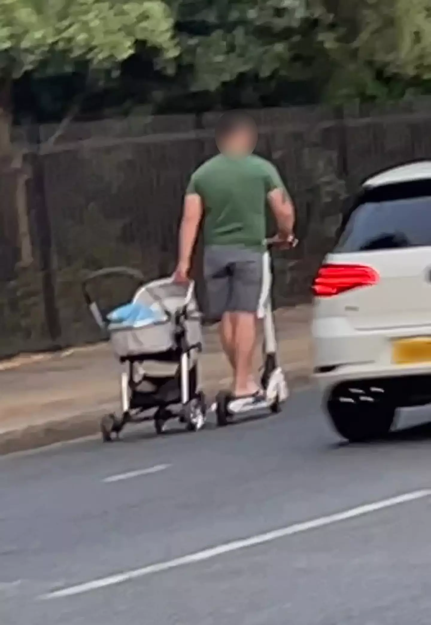 Cars brushed close past the man and his pram.