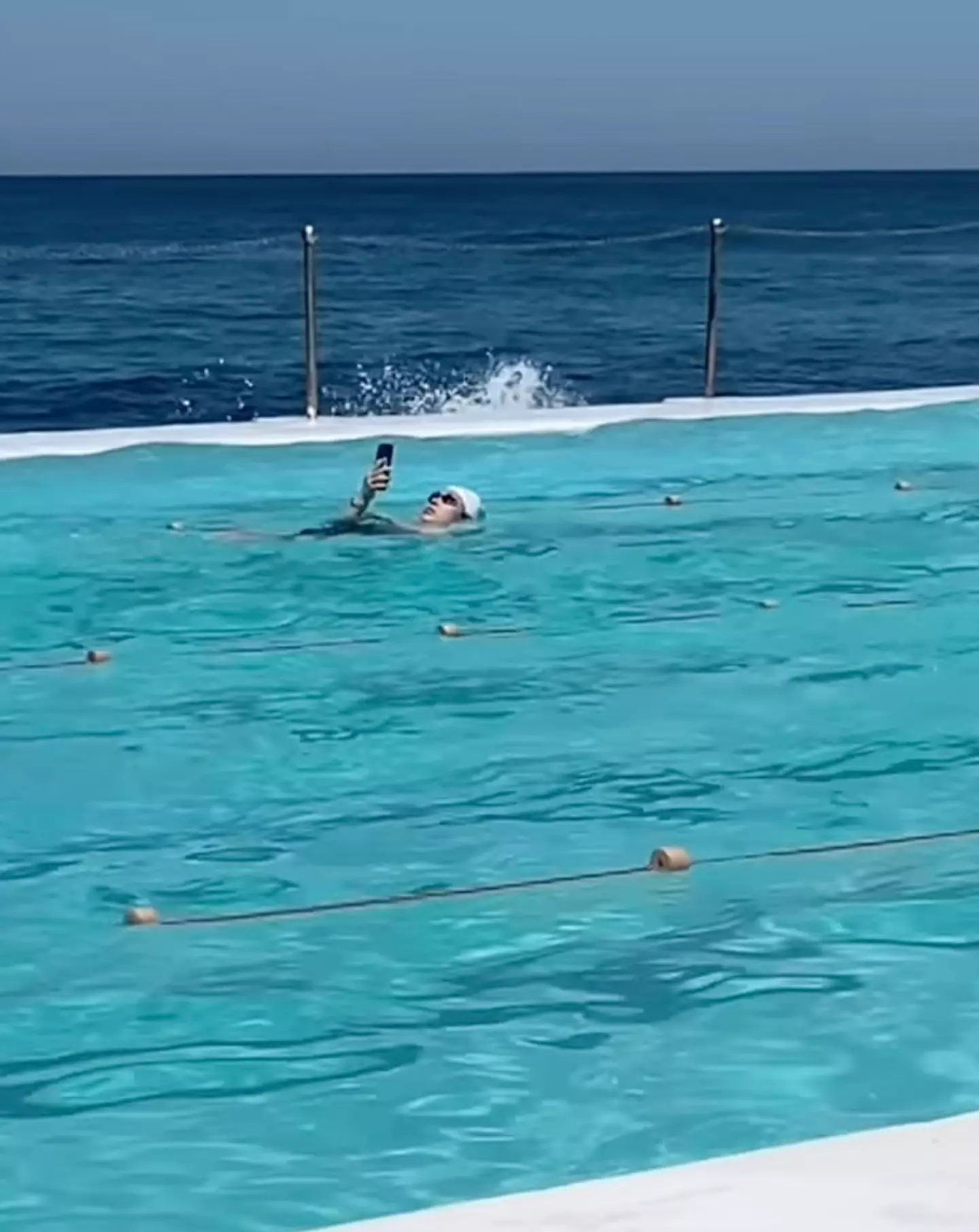 The mystery swimmer was seen scrolling in the pool in the viral video (Instagram/@browncardigan)