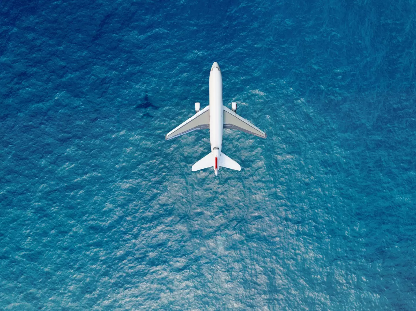 Stock image of a plane flying over the sea.