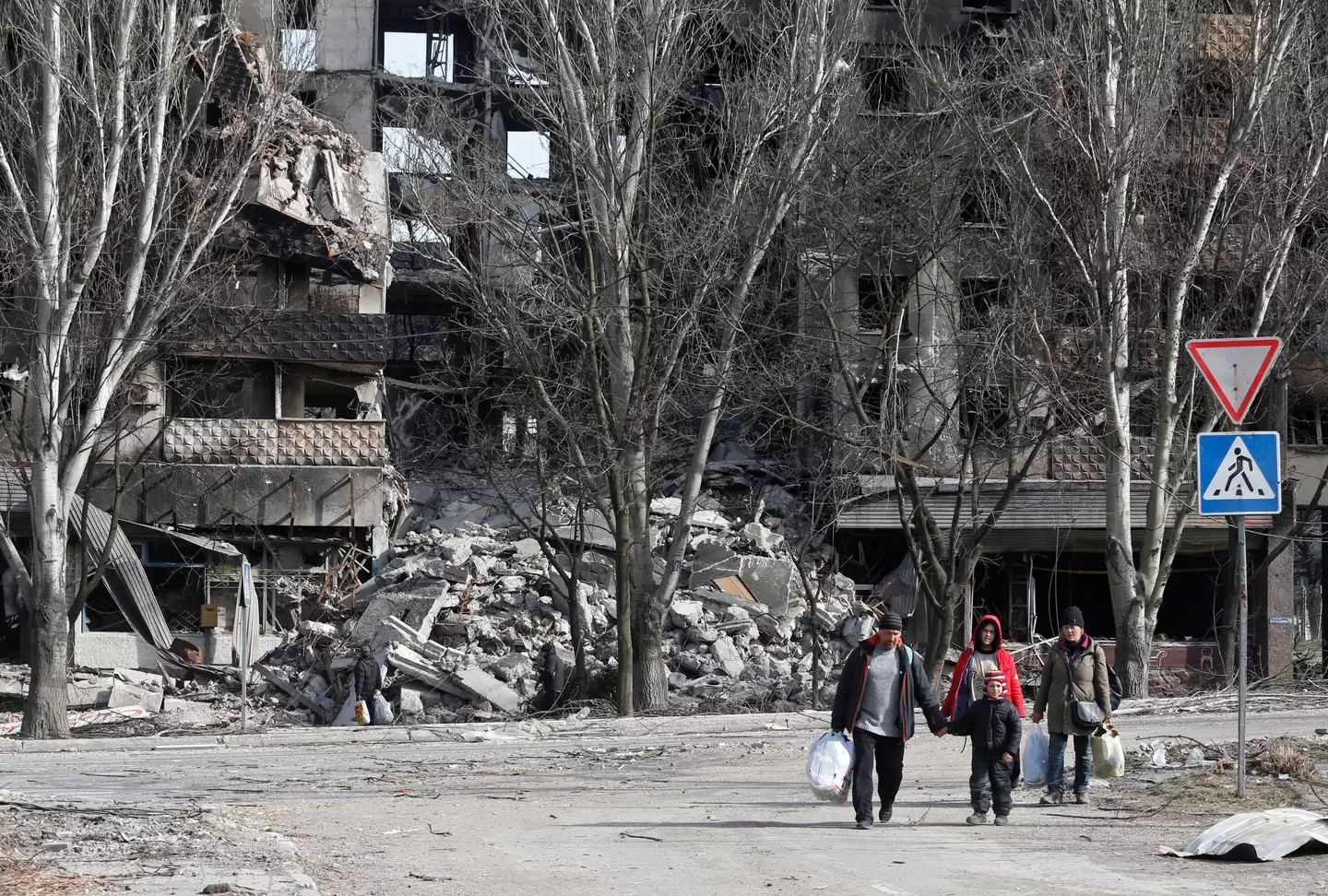 Local residents walk past an apartment building destroyed during Ukraine-Russia conflict in the besieged southern port city of Mariupol, Ukraine March 31, 2022.