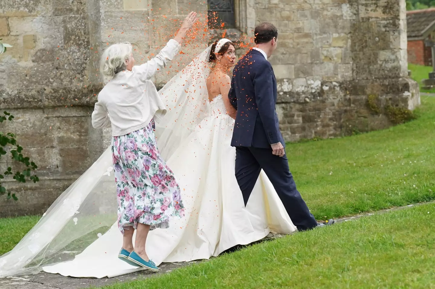 The woman threw orange confetti over the newlyweds.