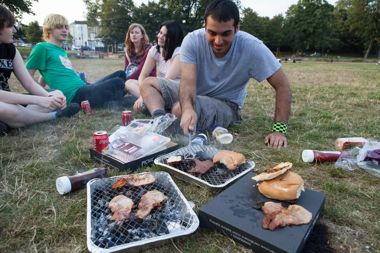 A group of friends enjoying a disposable barbecue in the park.