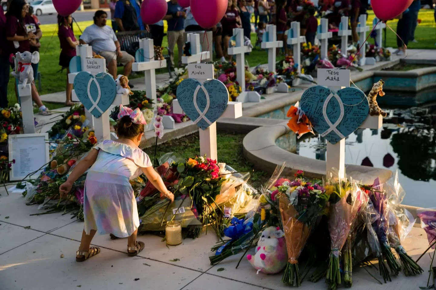 Girl lays wreath at er teachers memorial cross after she was killed in Uvalde.