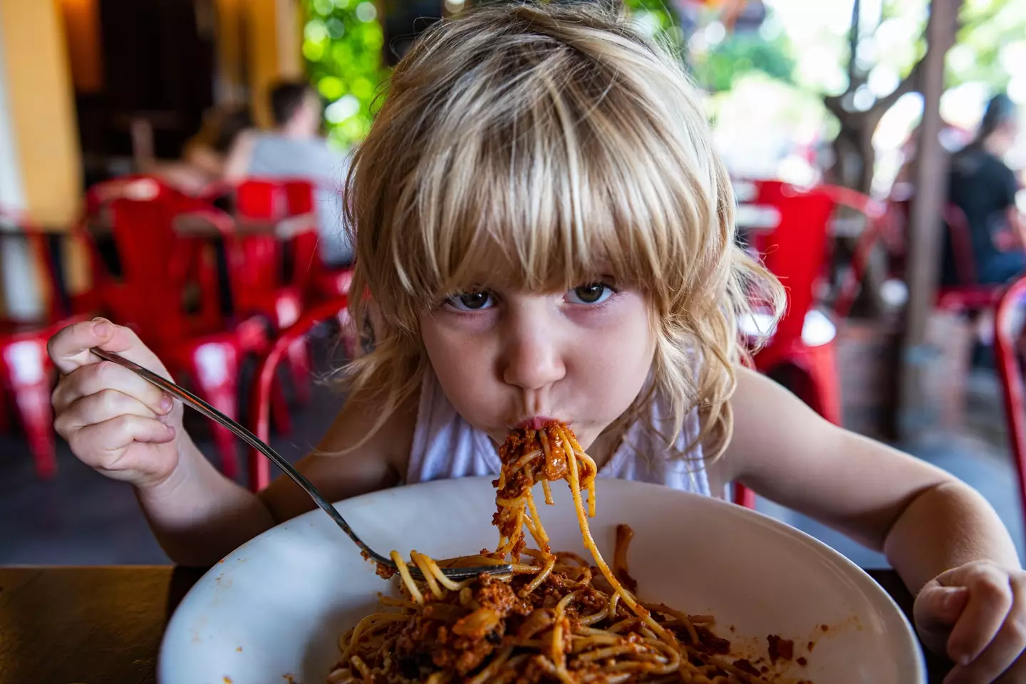 Stock image of child eating spaghetti in restaurant.