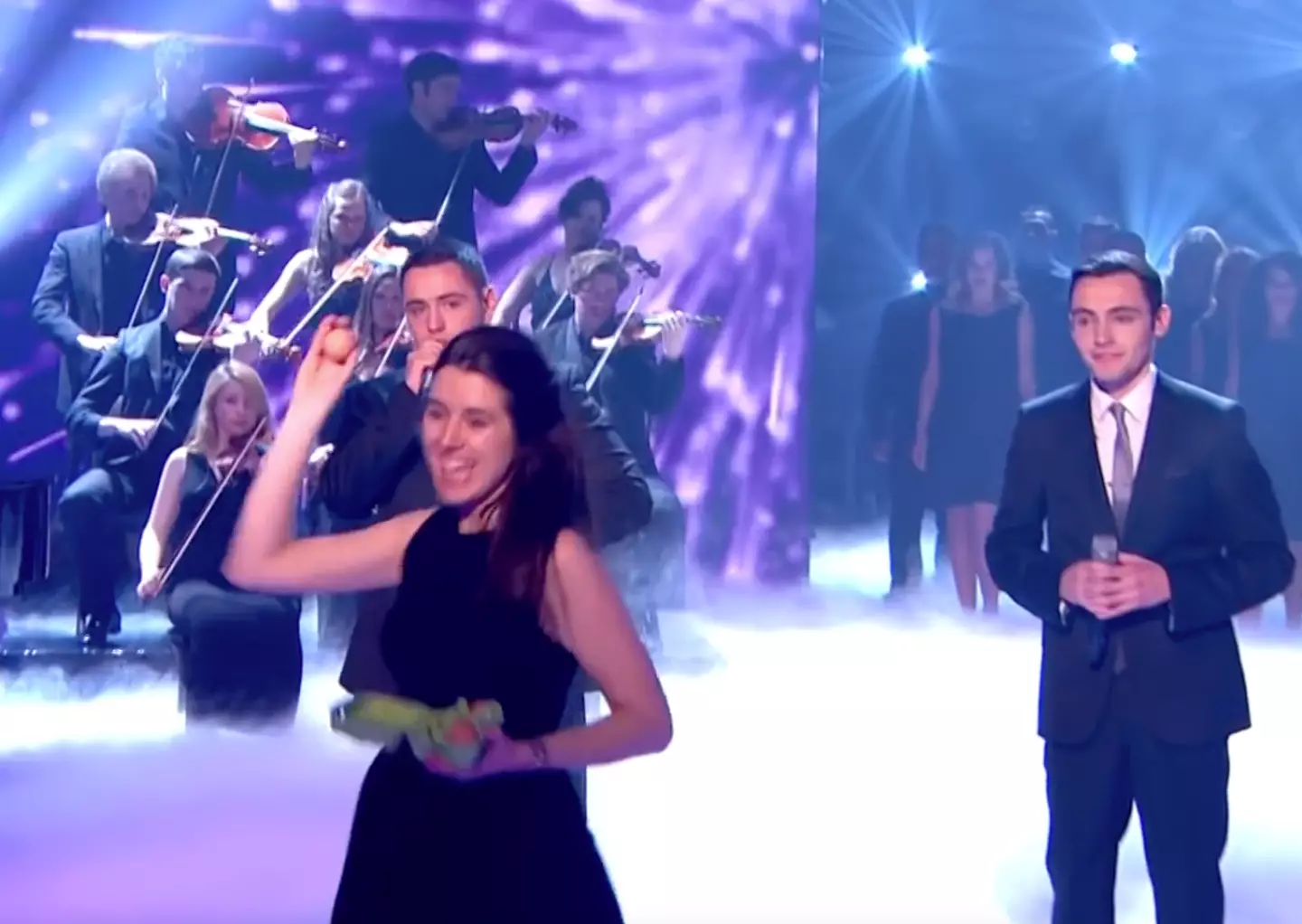 In the midst of their 2013 final performance, singers Richard and Adam Johnson were unsurprisingly unshaken when a violinist named Natalie Holt emerged from the orchestra behind them - with what looked like a half dozen eggs in her hand.