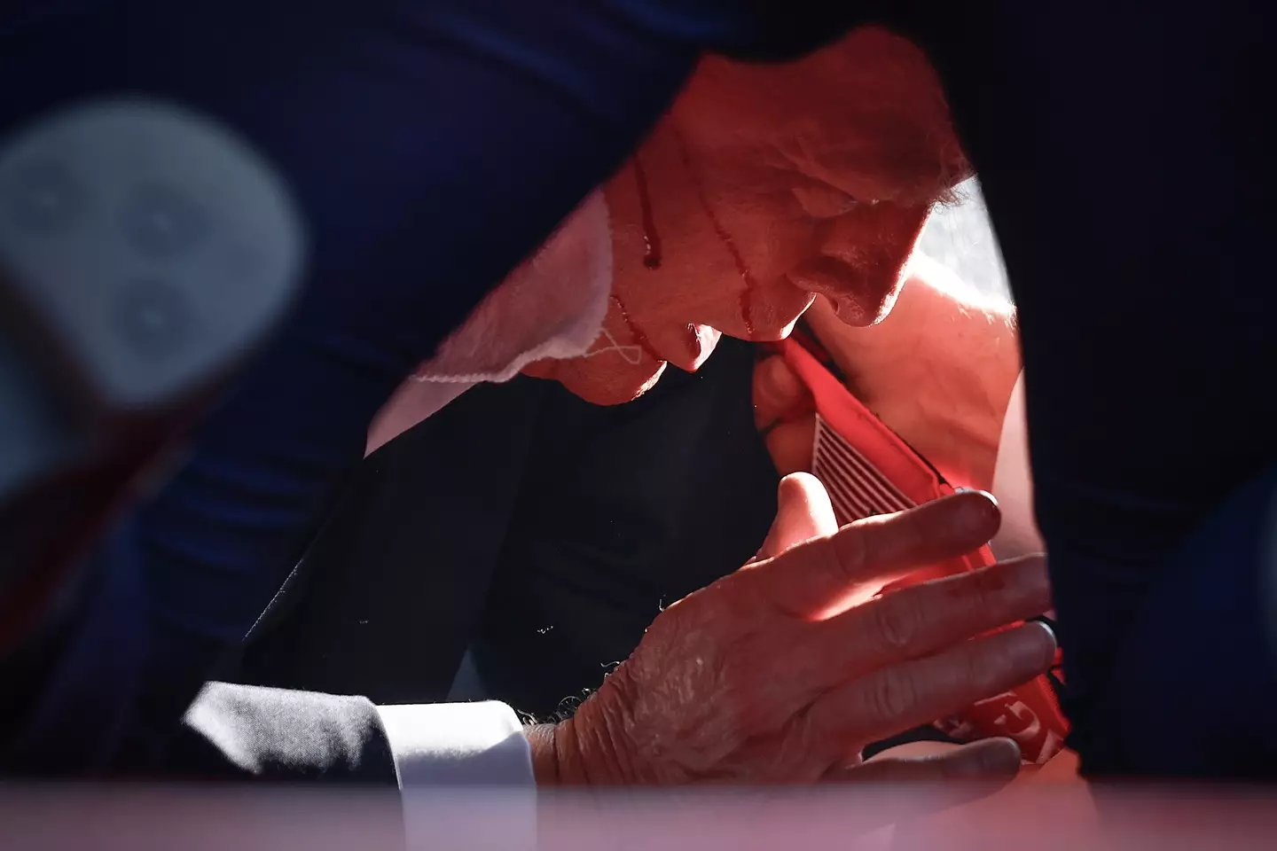 Trump takes cover beneath the podium after a bullet grazed his ear. (Anna Moneymaker/Getty Images)