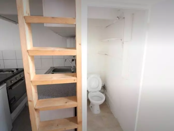 The toilet sits next to the ladder to the bed... and has no door (