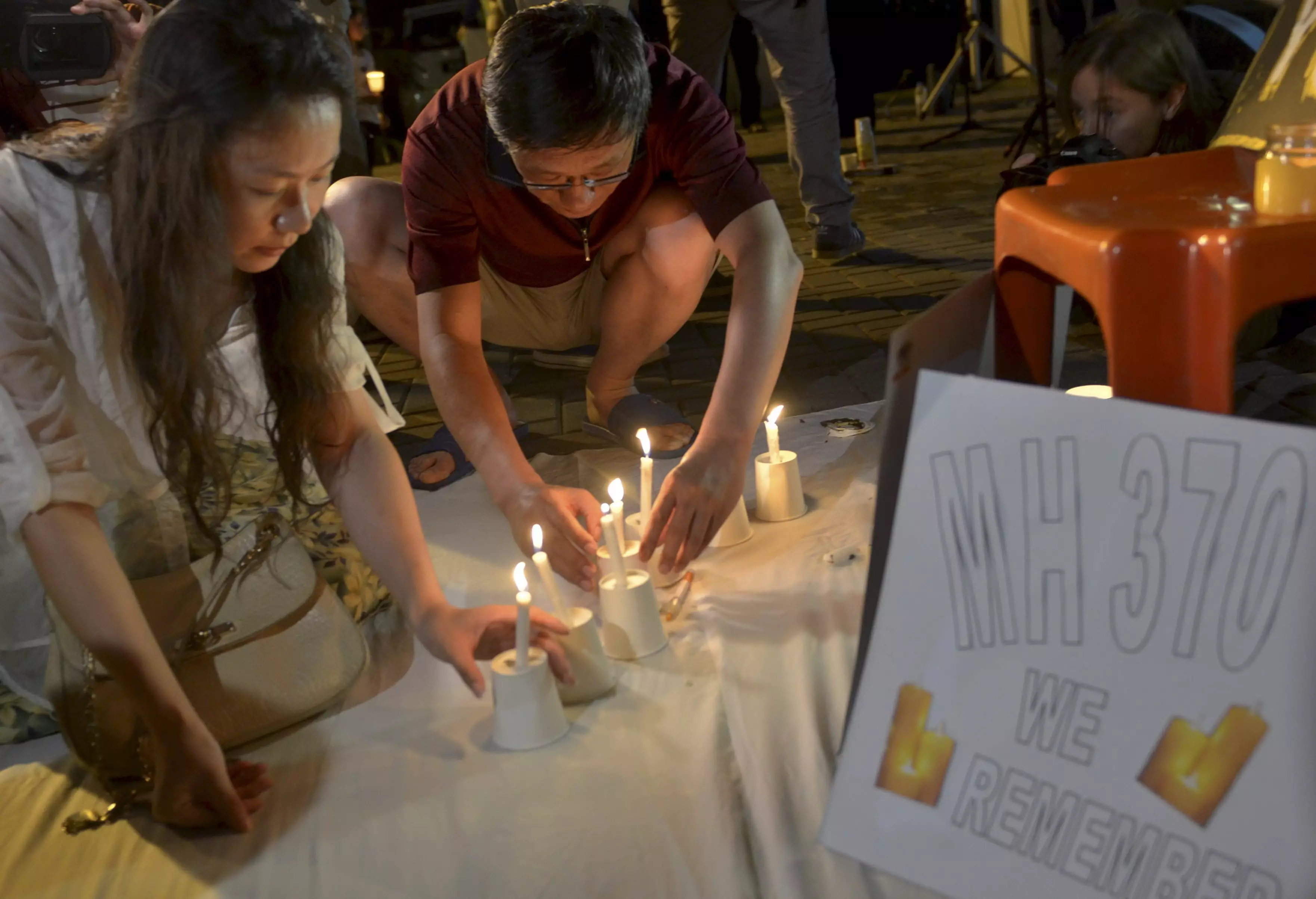 Kelly Wen (L), wife of a Chinese passenger Li who was on board MH370 light up a candle during vigil.
