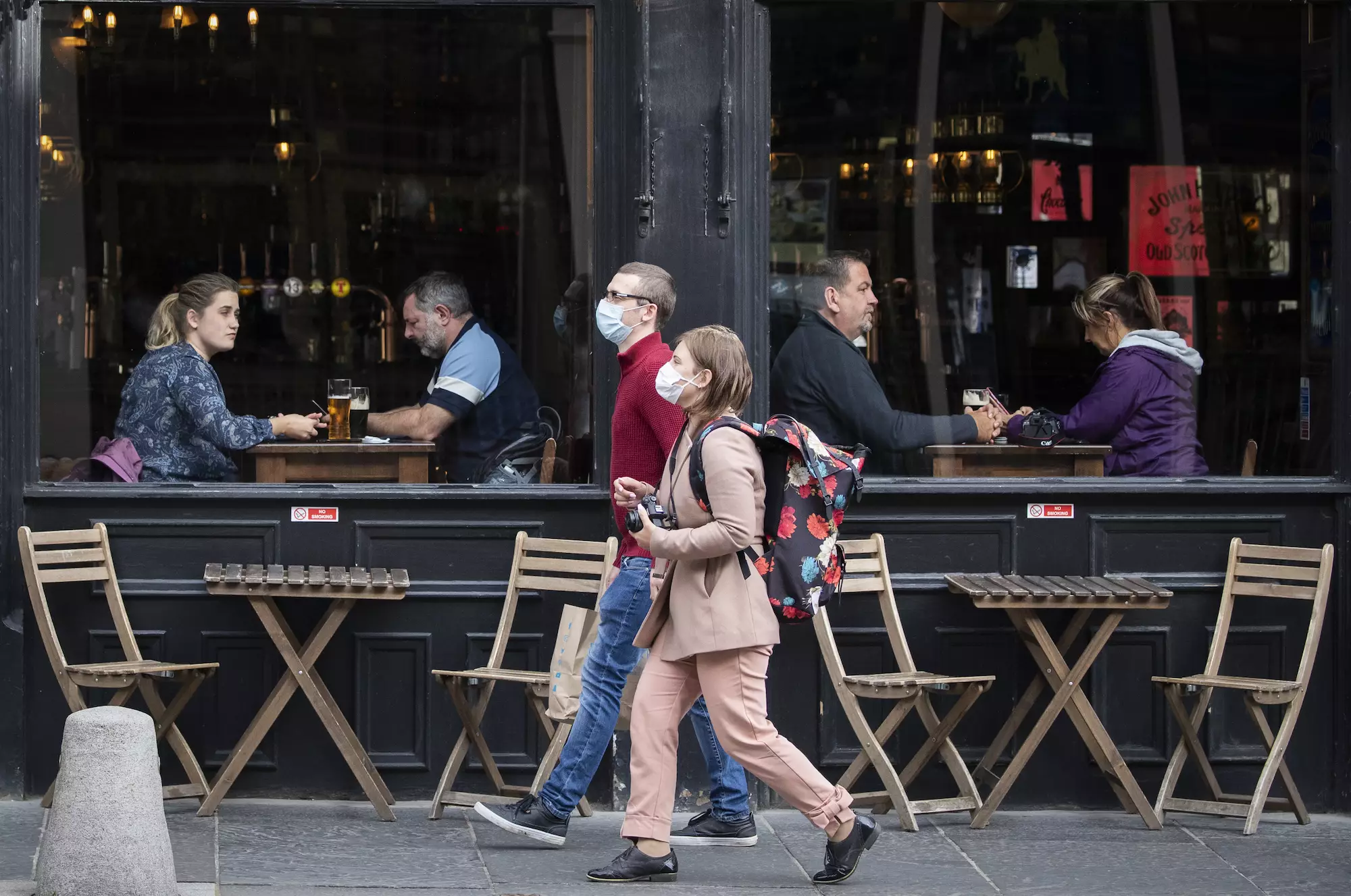 People wearing protective face masks walk past a bar in Edinburgh city centre (